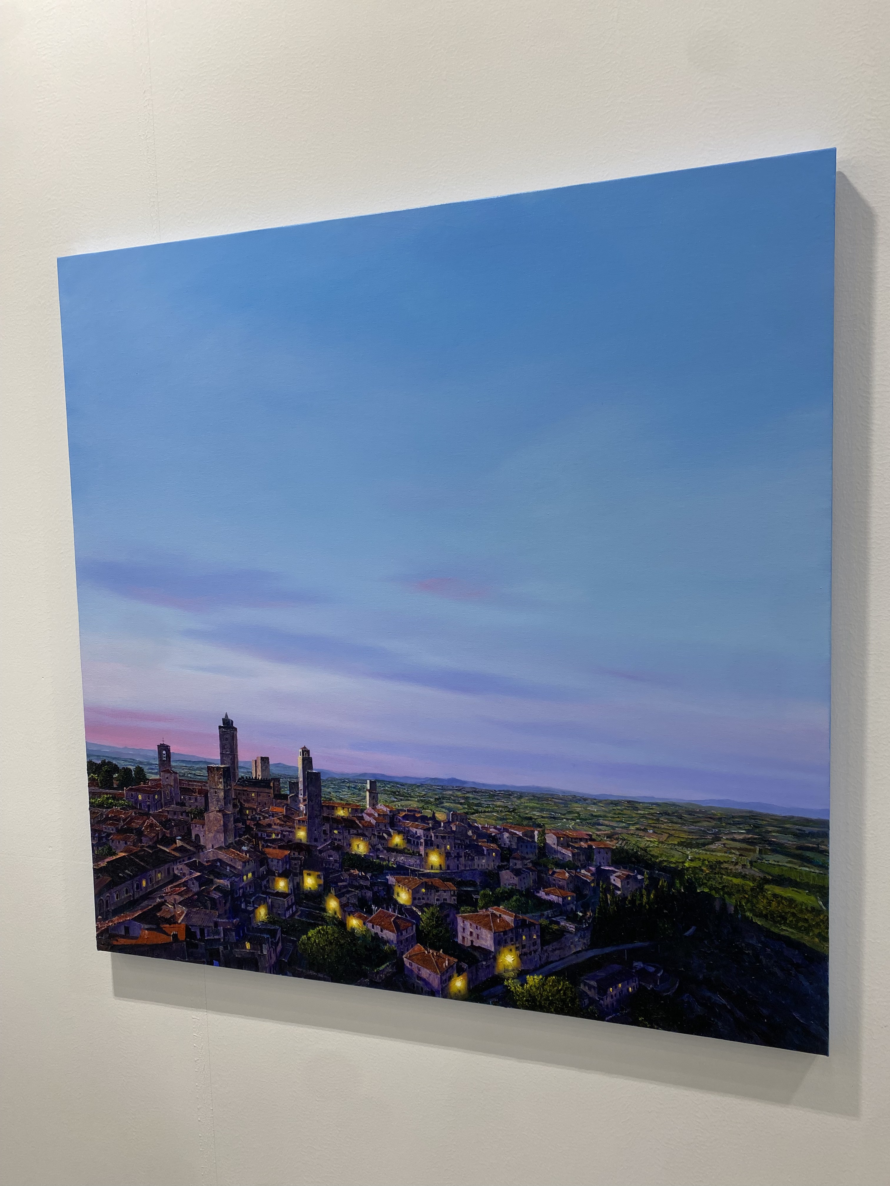 A painting of a city at dusk with a blue sky.