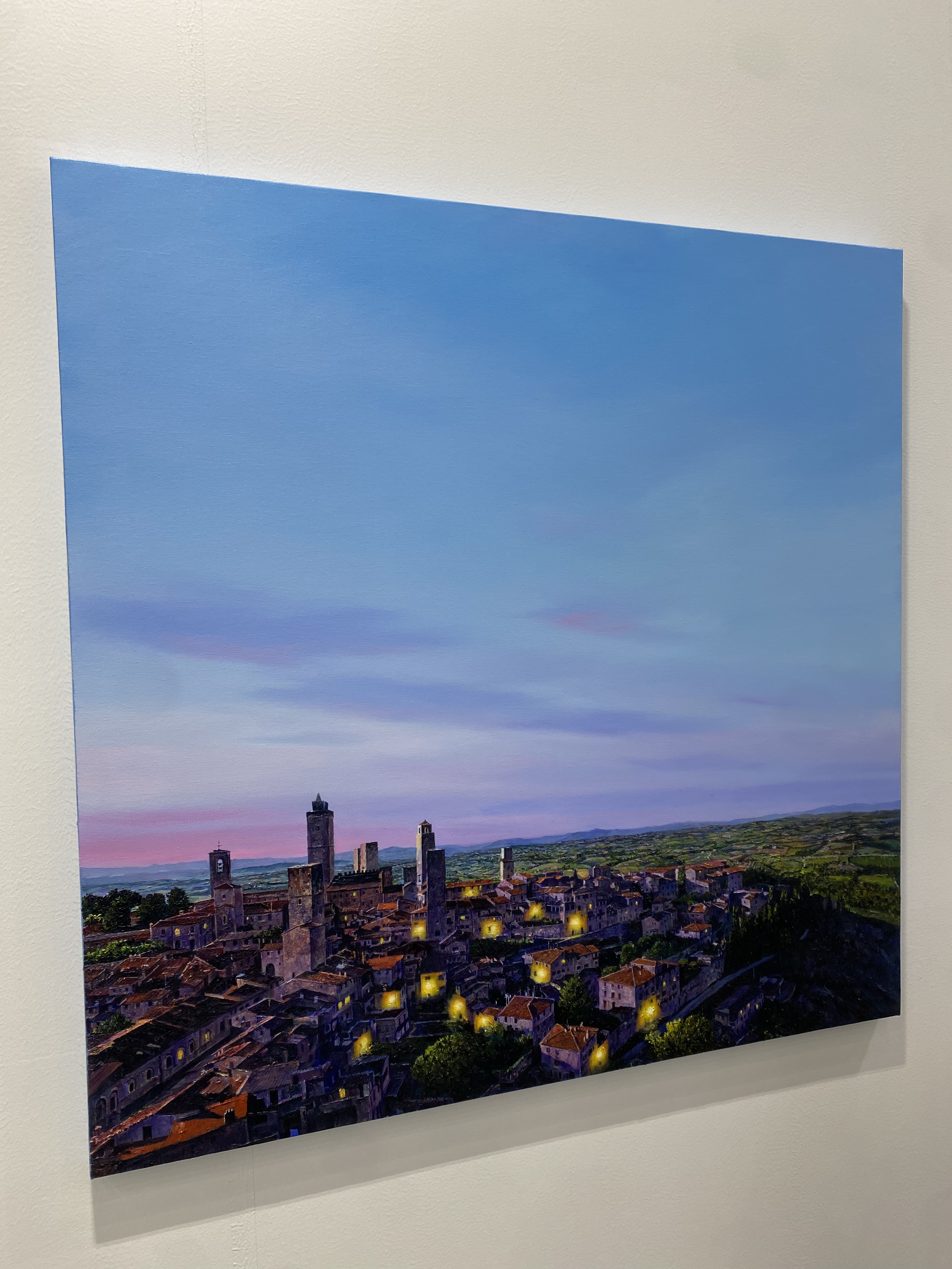 A painting of a city at dusk with a blue sky.