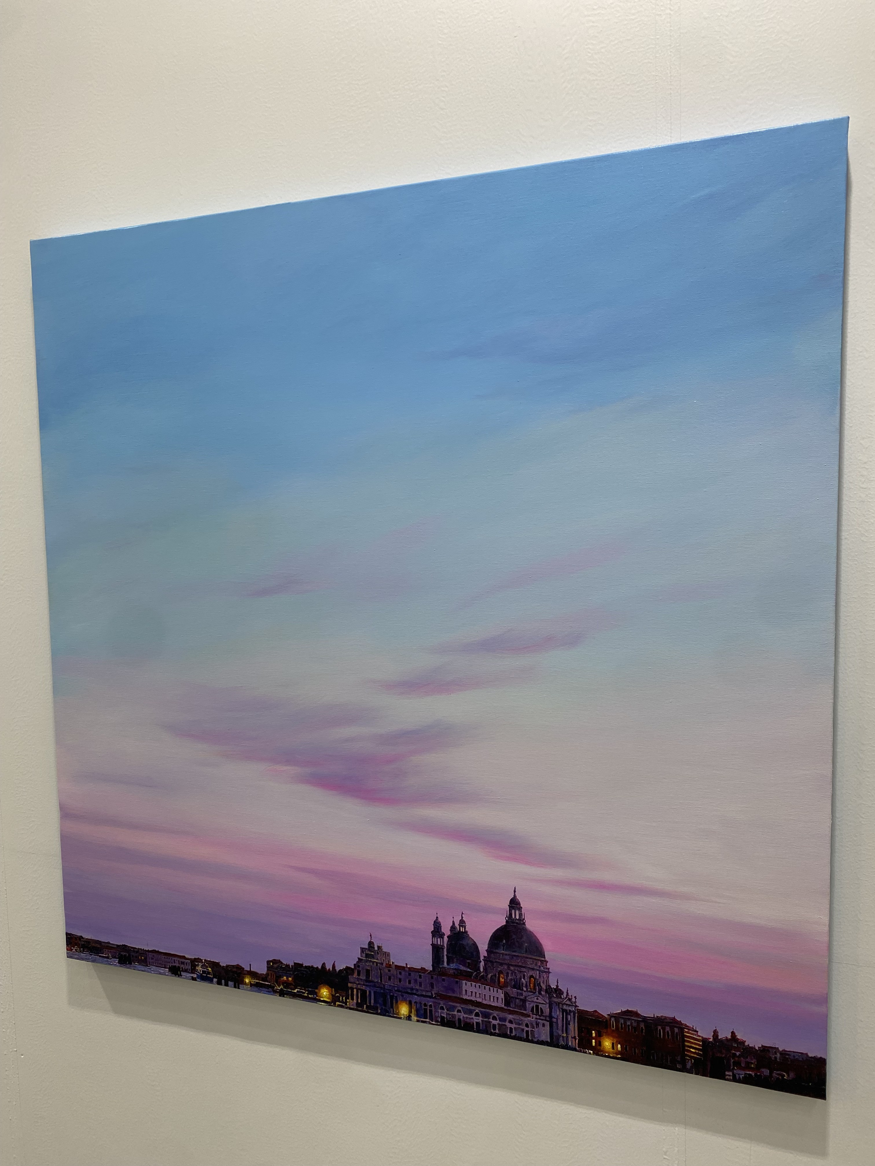 A view of a city skyline at dusk with a church in the background.