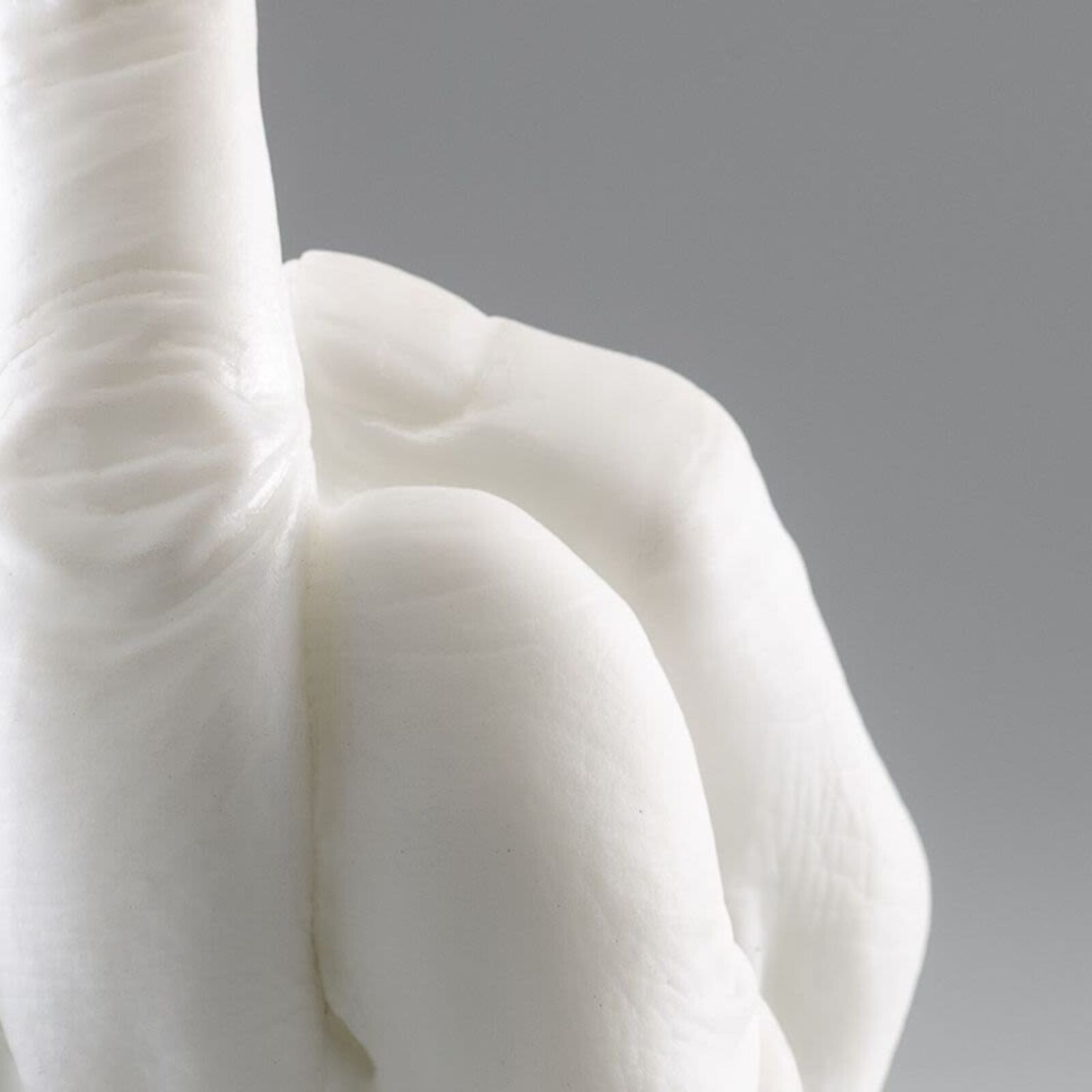 A white sculpture of a hand making a peace sign.