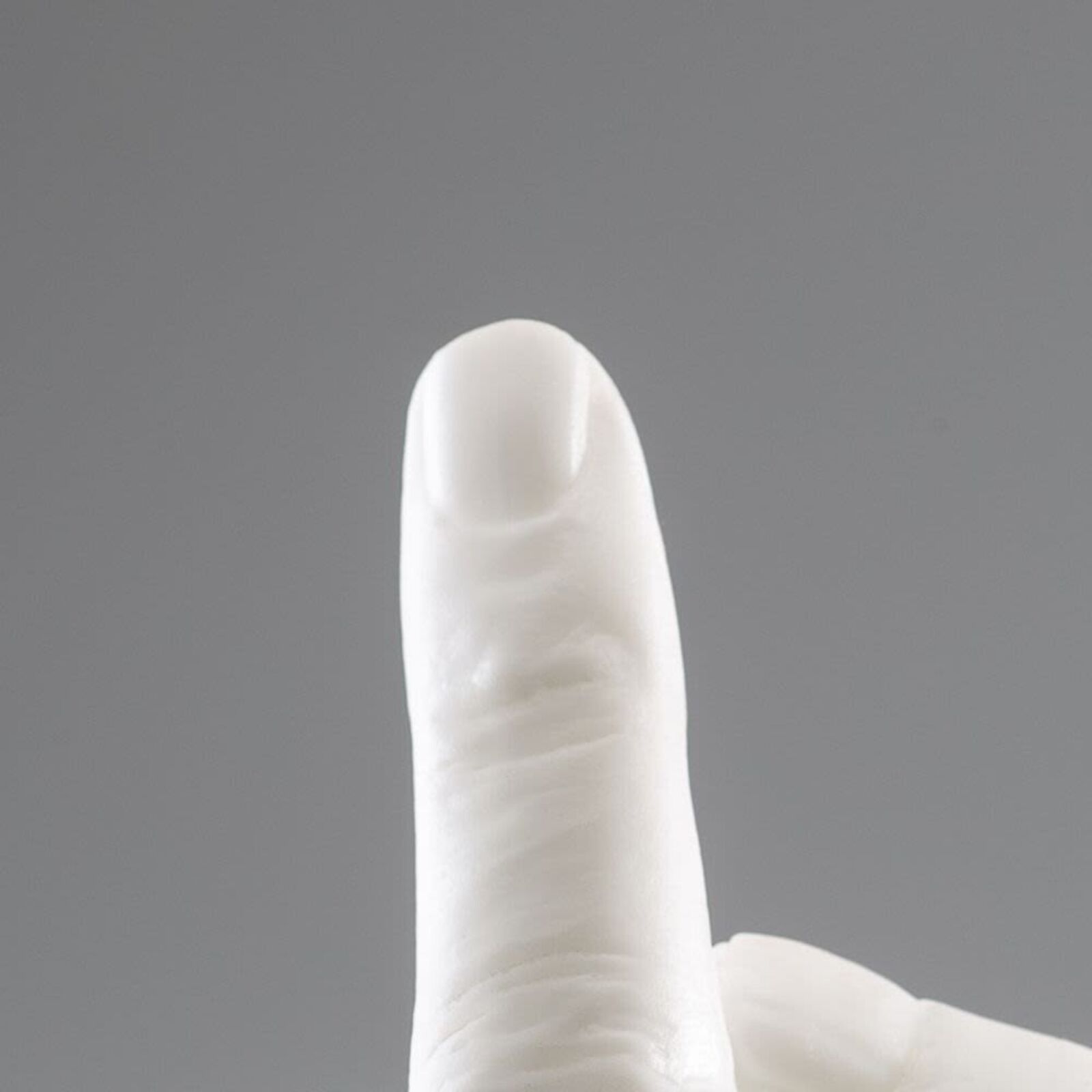 A white sculpture of a hand making a peace sign.