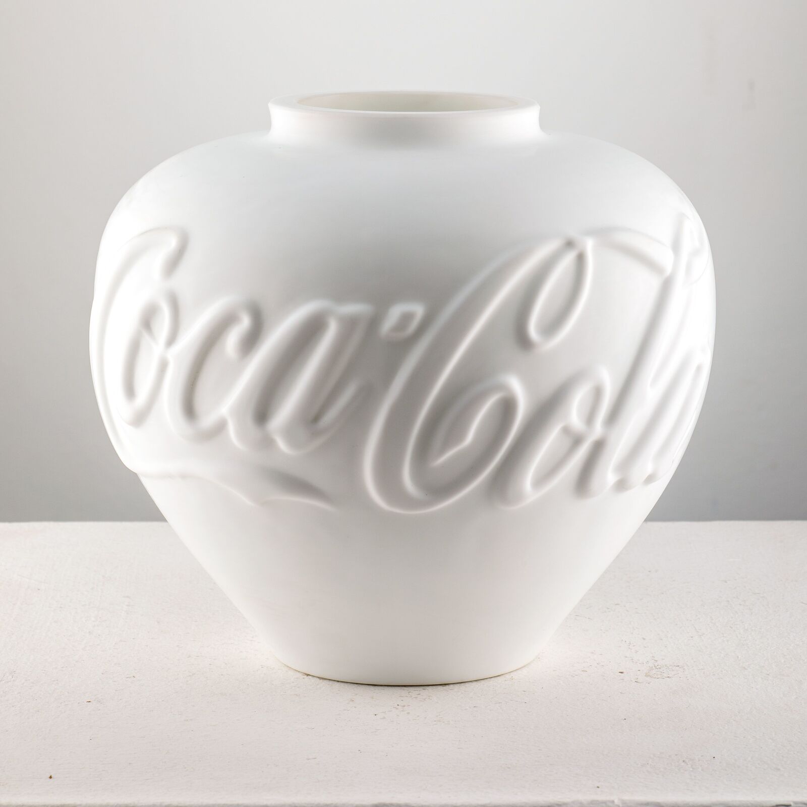 A group of coca cola vases sitting next to each other.