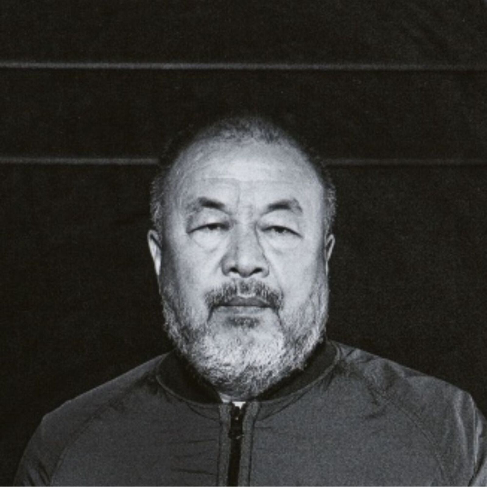 A man in a black jacket standing in a dark room.