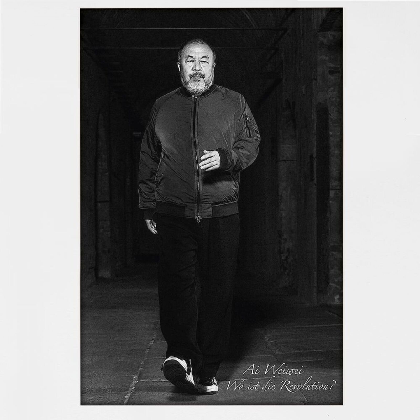 A man in a black jacket standing in a dark room.