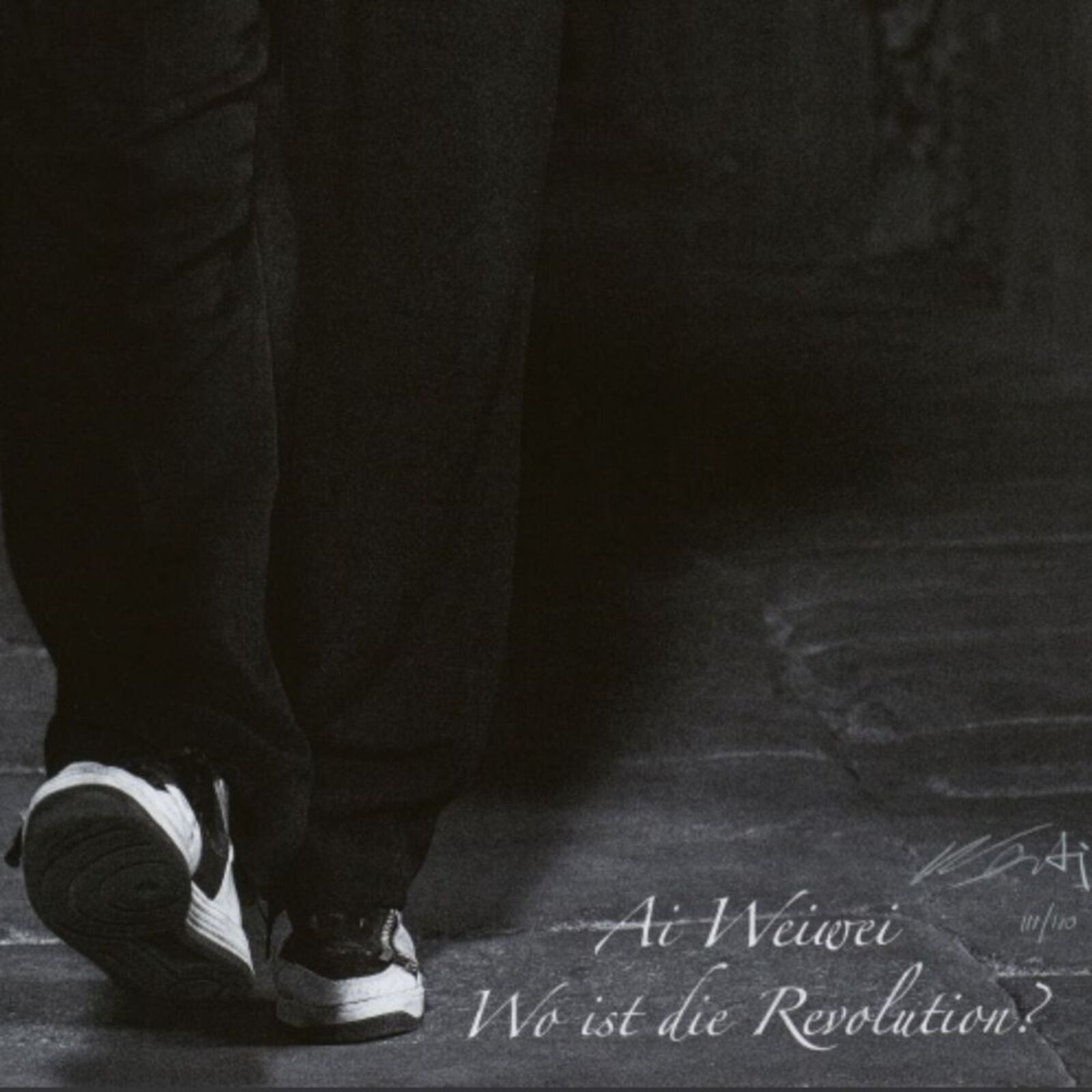 A man in a black jacket standing in a dark room.