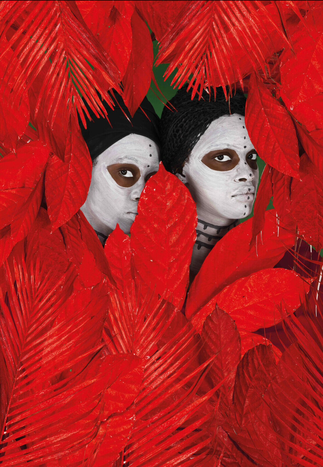 A couple of people with white face paint and red feathers.