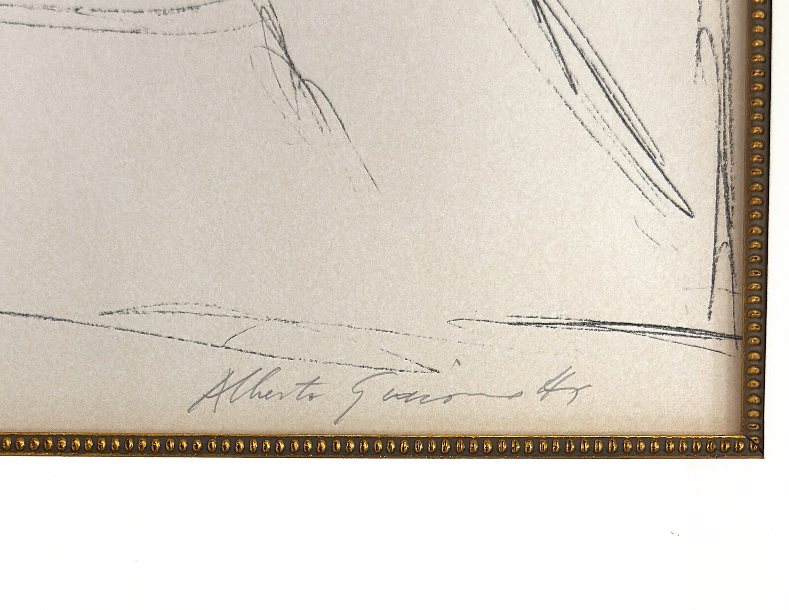 A graphite sketch of a seated nude figure in a studio setting.