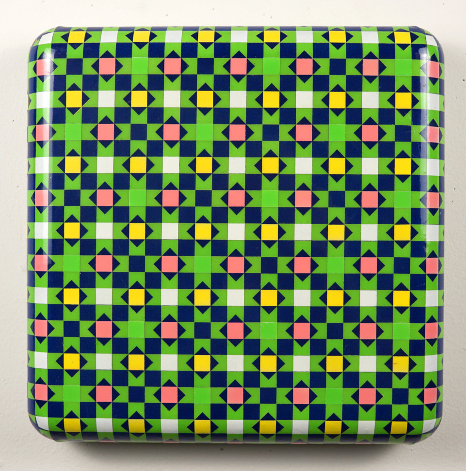 A glossy square box featuring a vibrant, geometric pattern of repeating diamonds and squares in bold primary colors.