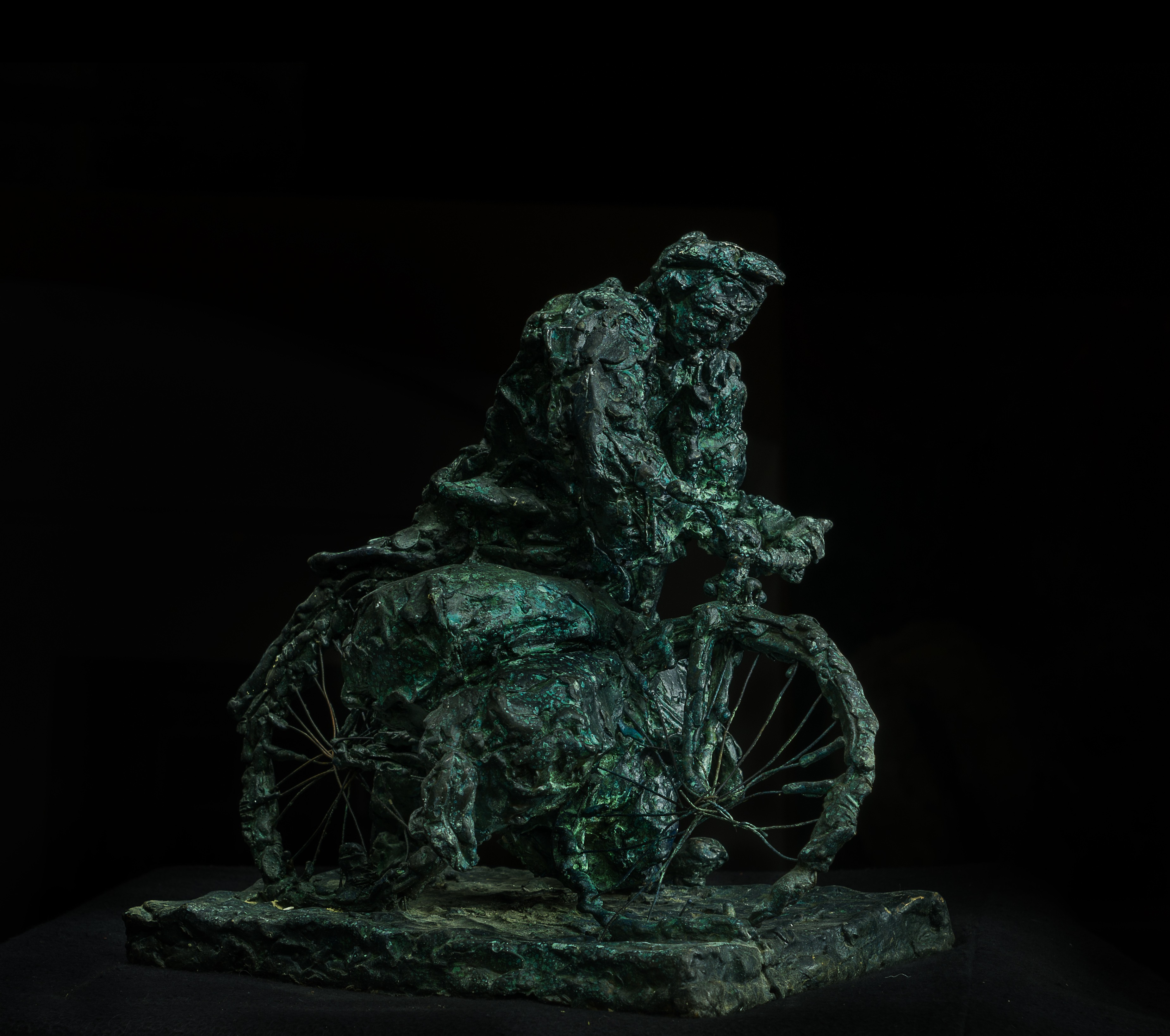 A bronze sculpture of a man sitting on a rock.