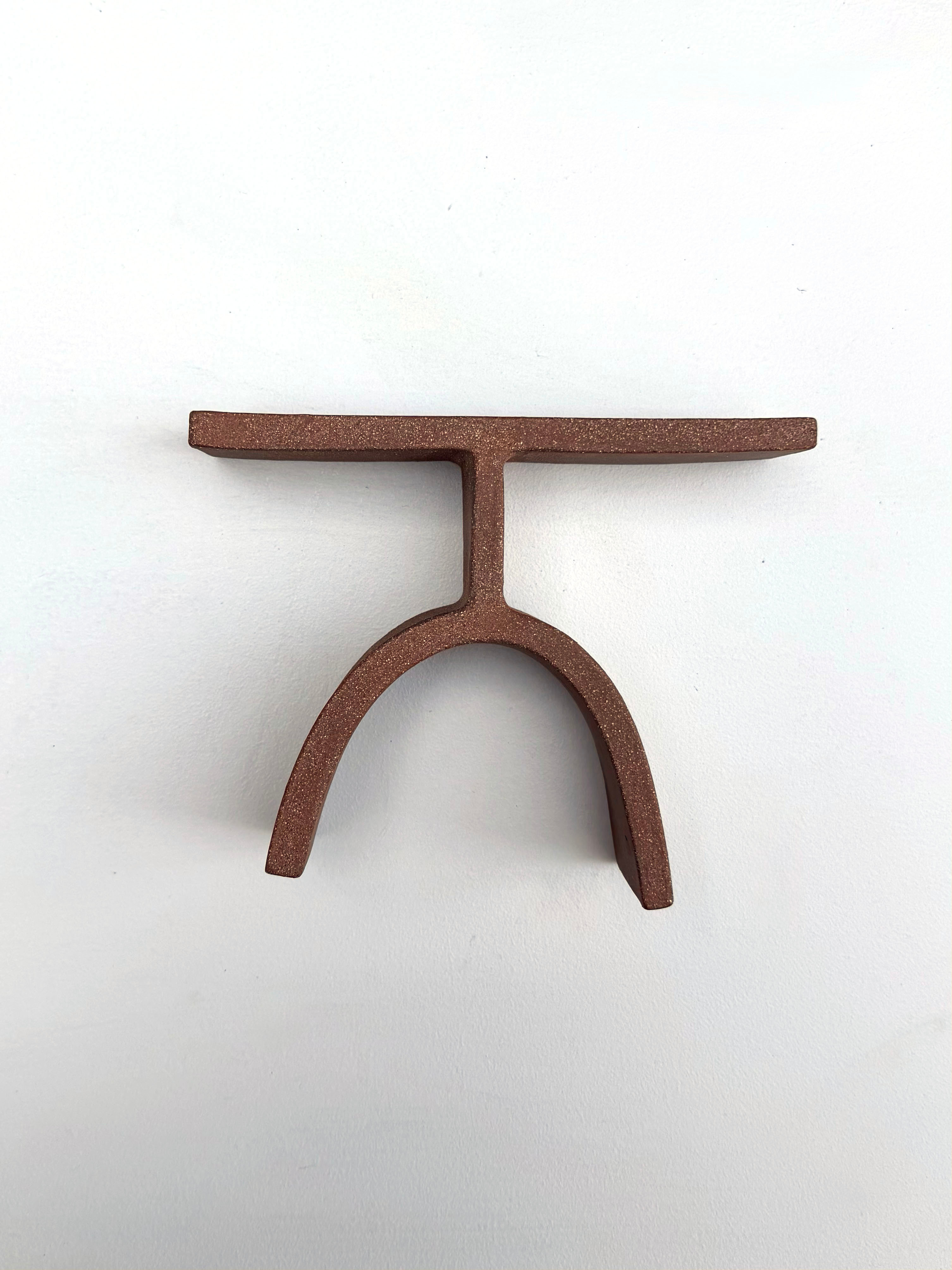 A brown metal object on a white surface.