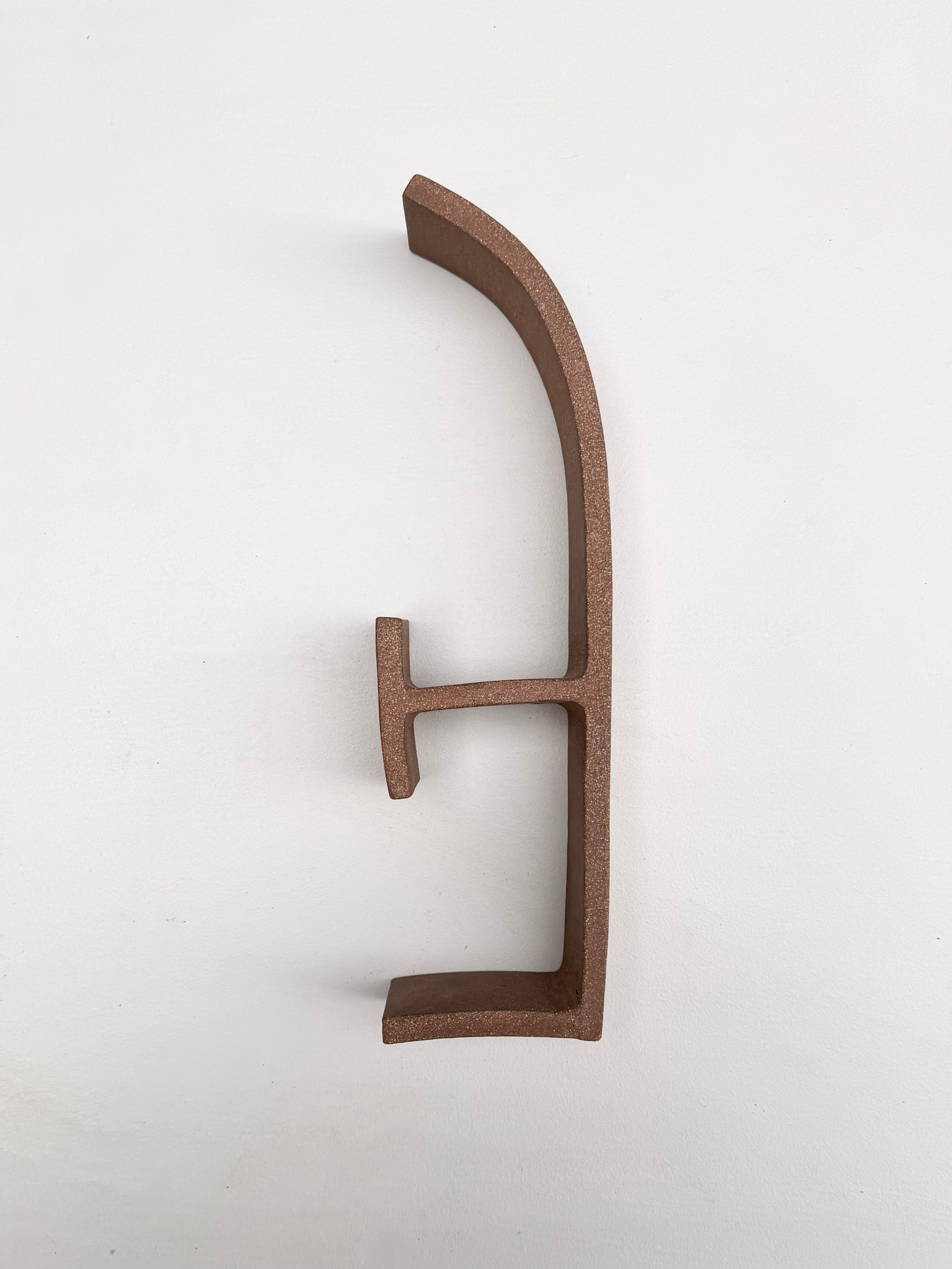 A metal letter E on a white wall.