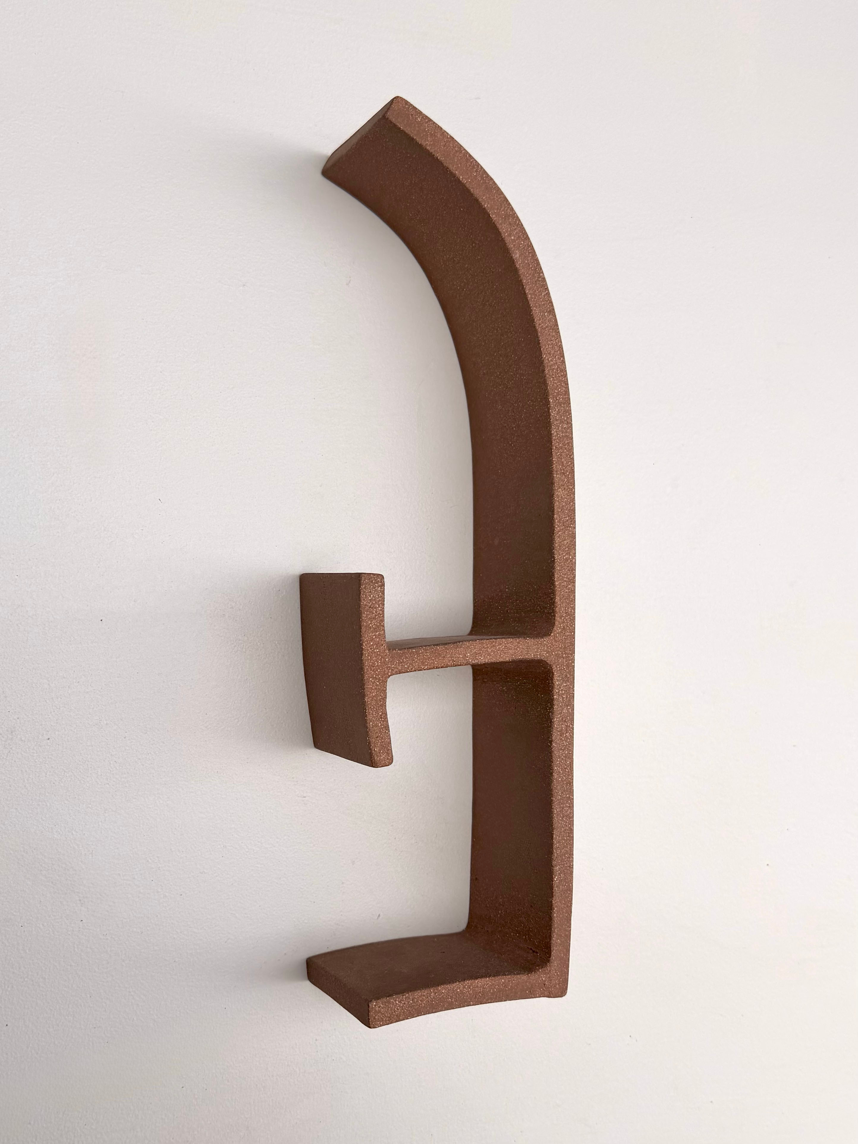 A metal letter E on a white wall.