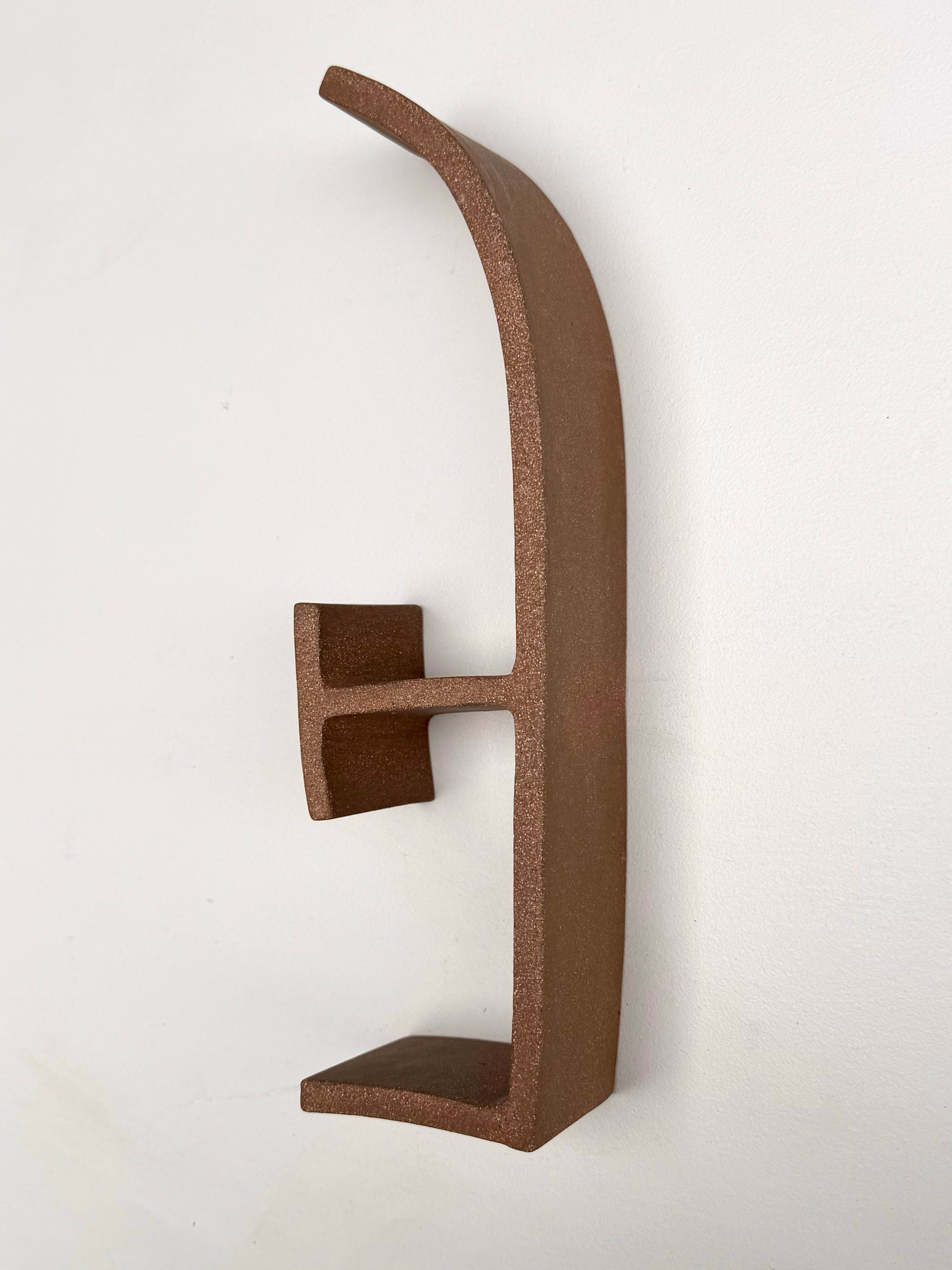 A metal letter E on a white wall.