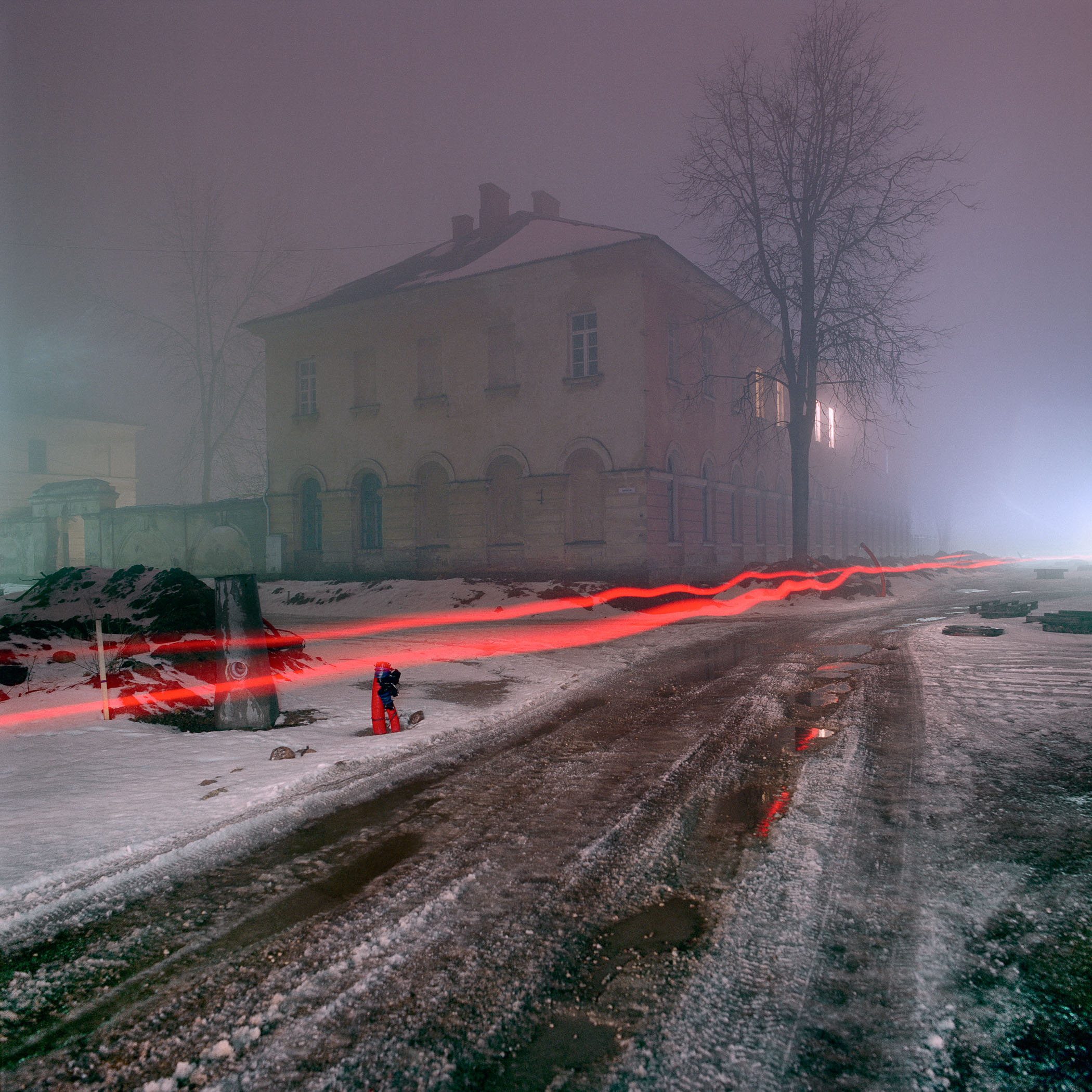 A person walking down a snowy road in front of a building.