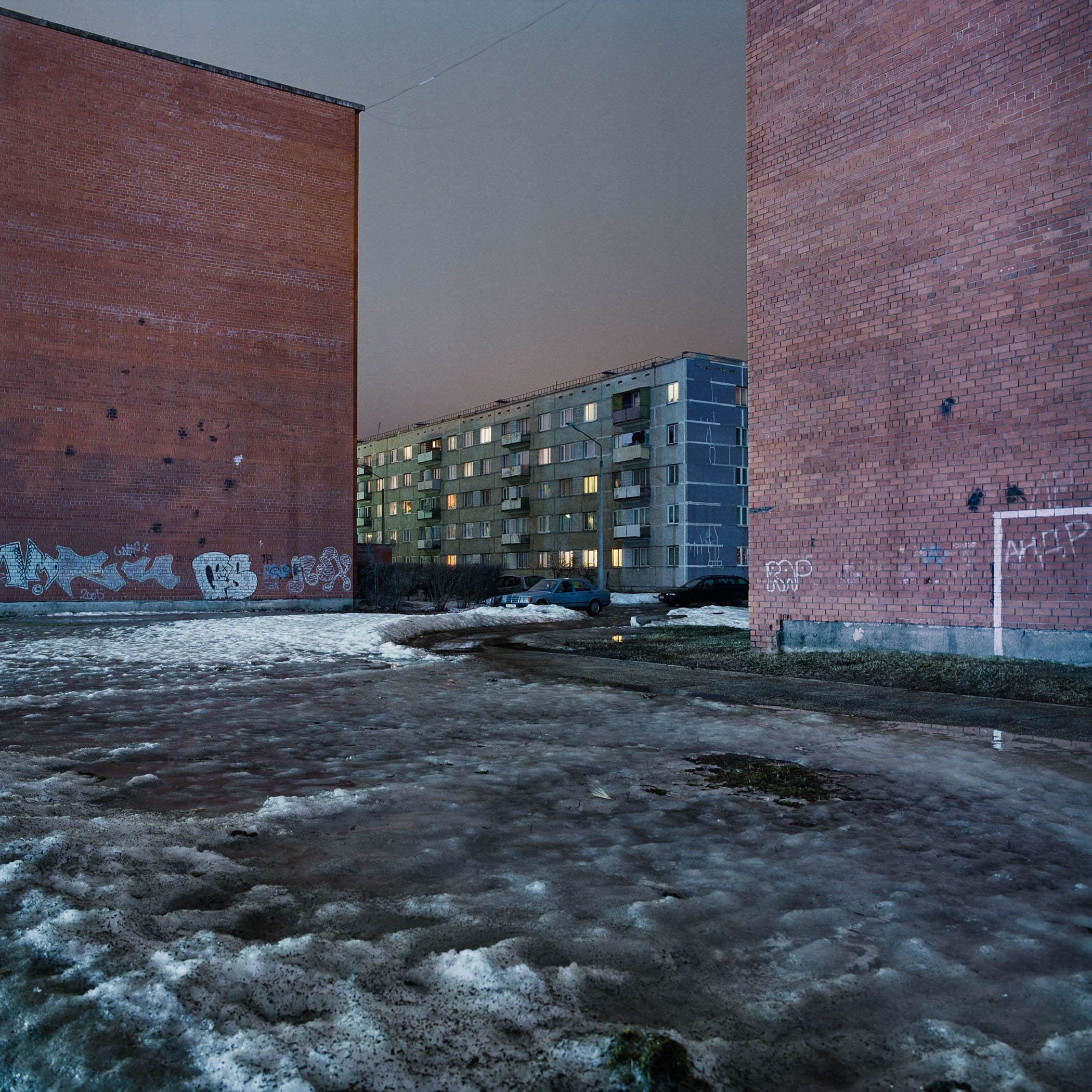 A parking lot with a car parked in front of a brick building.