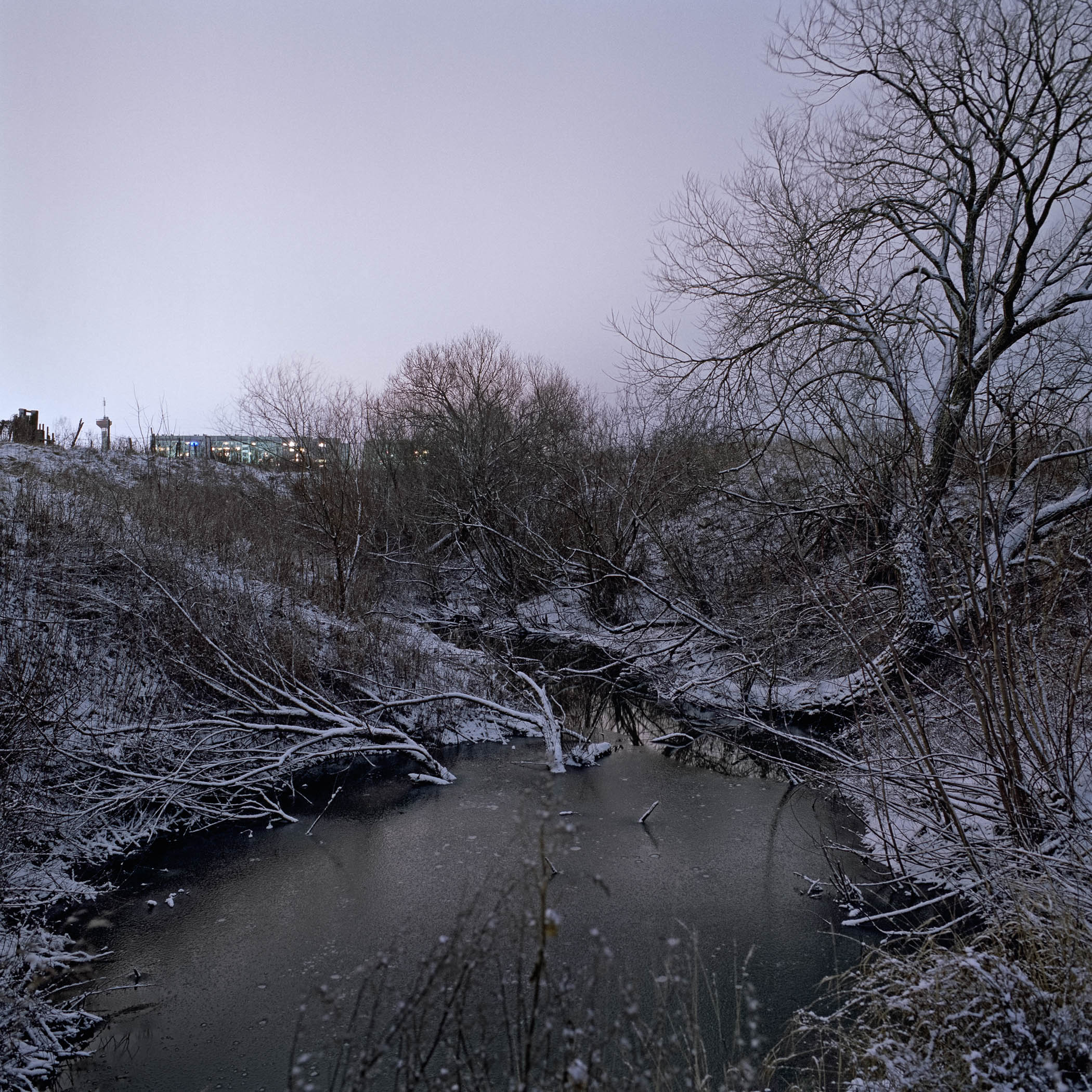A small stream running through a snow covered field.