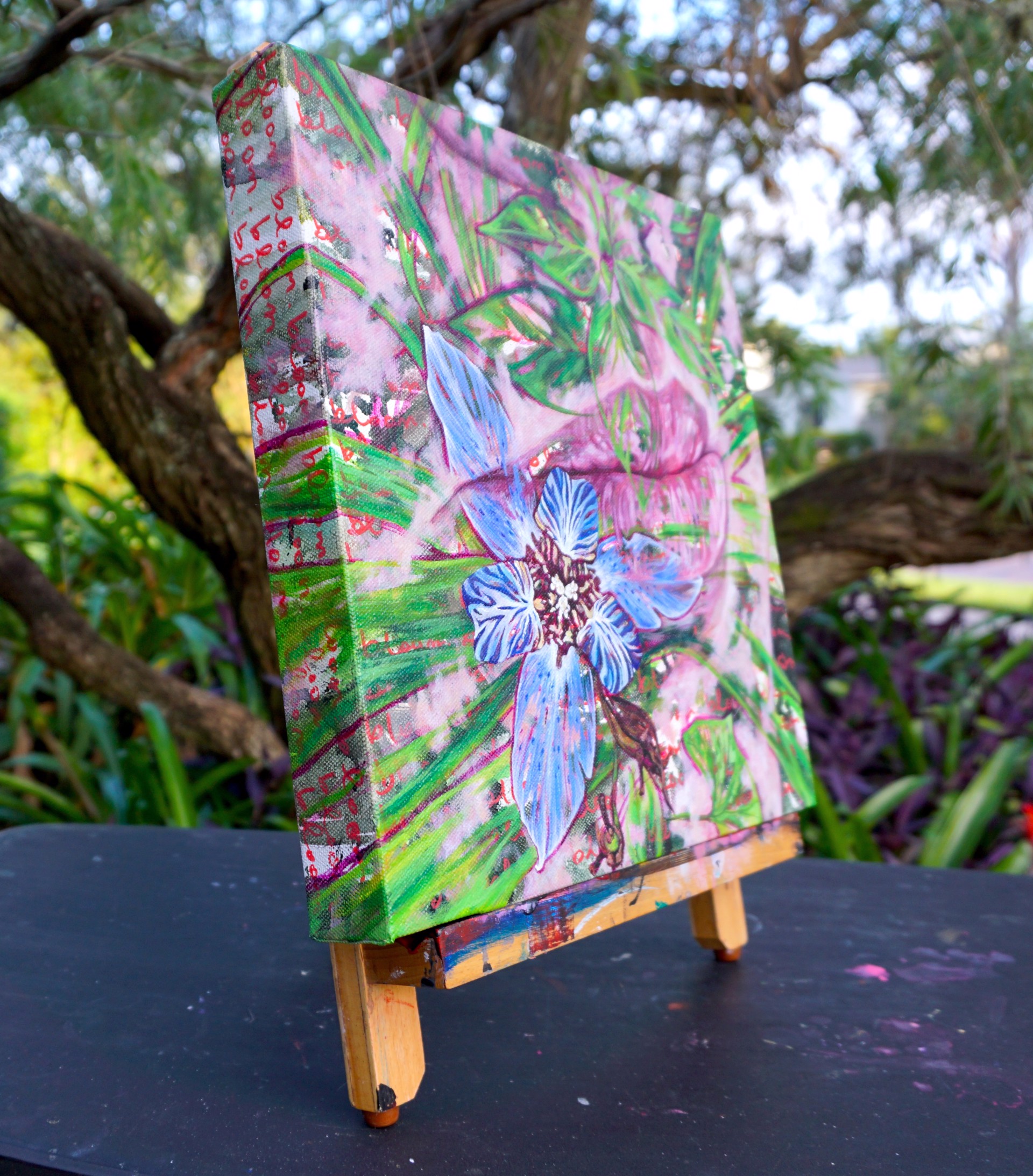 A painting of a blue flower on a pink background.
