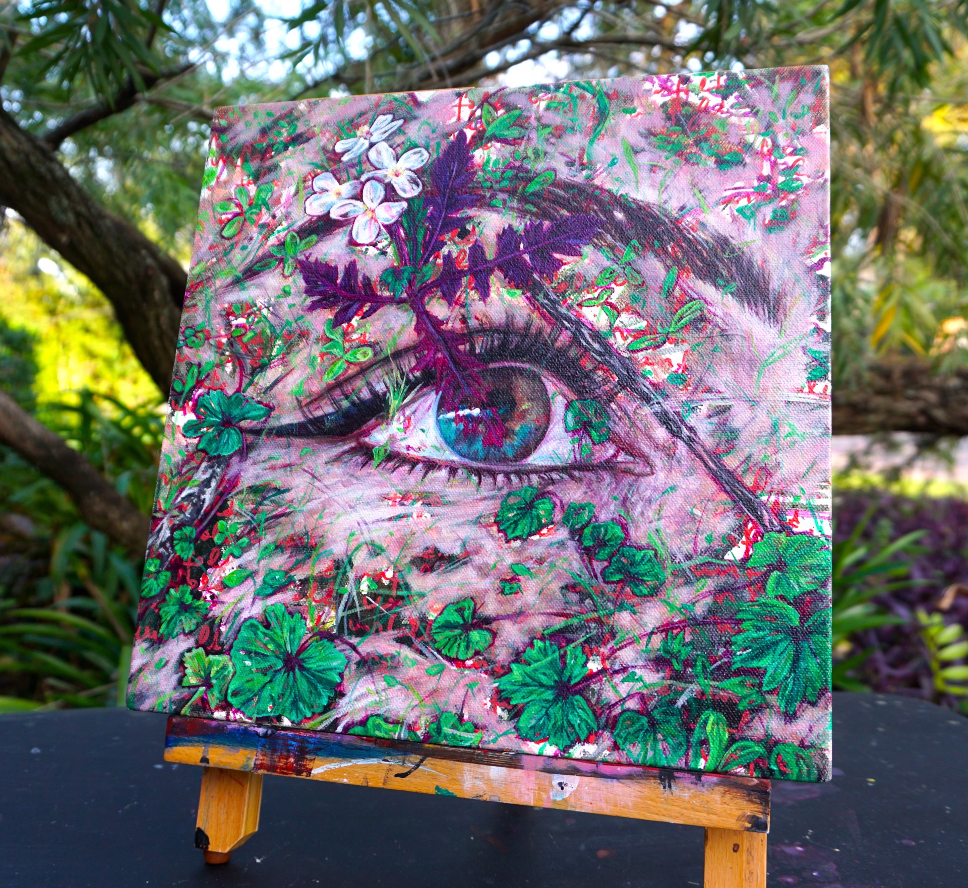 A painting of a woman's eye surrounded by flowers.