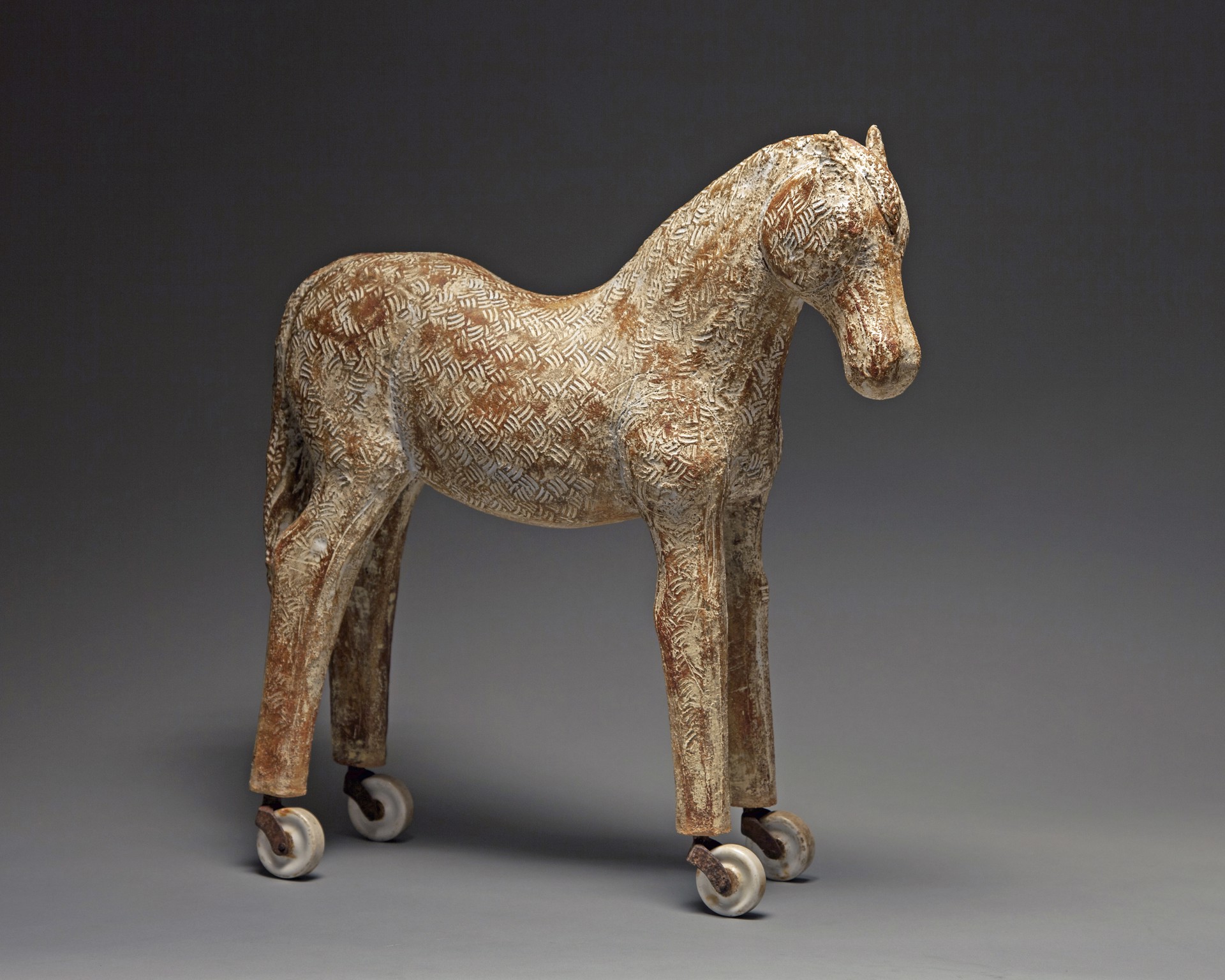 A wooden horse with wheels on a gray background.