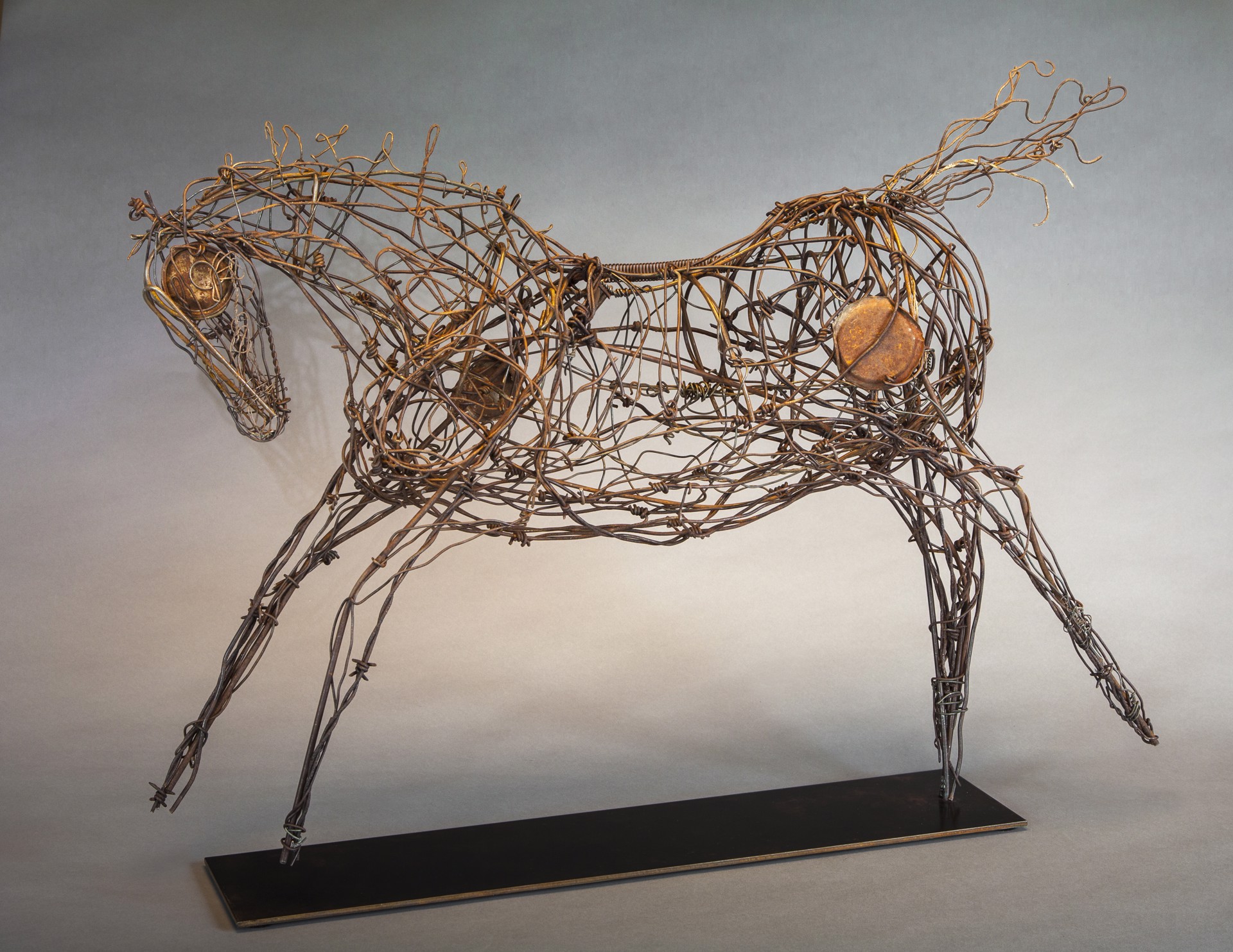 A wire sculpture of a horse on a metal stand.