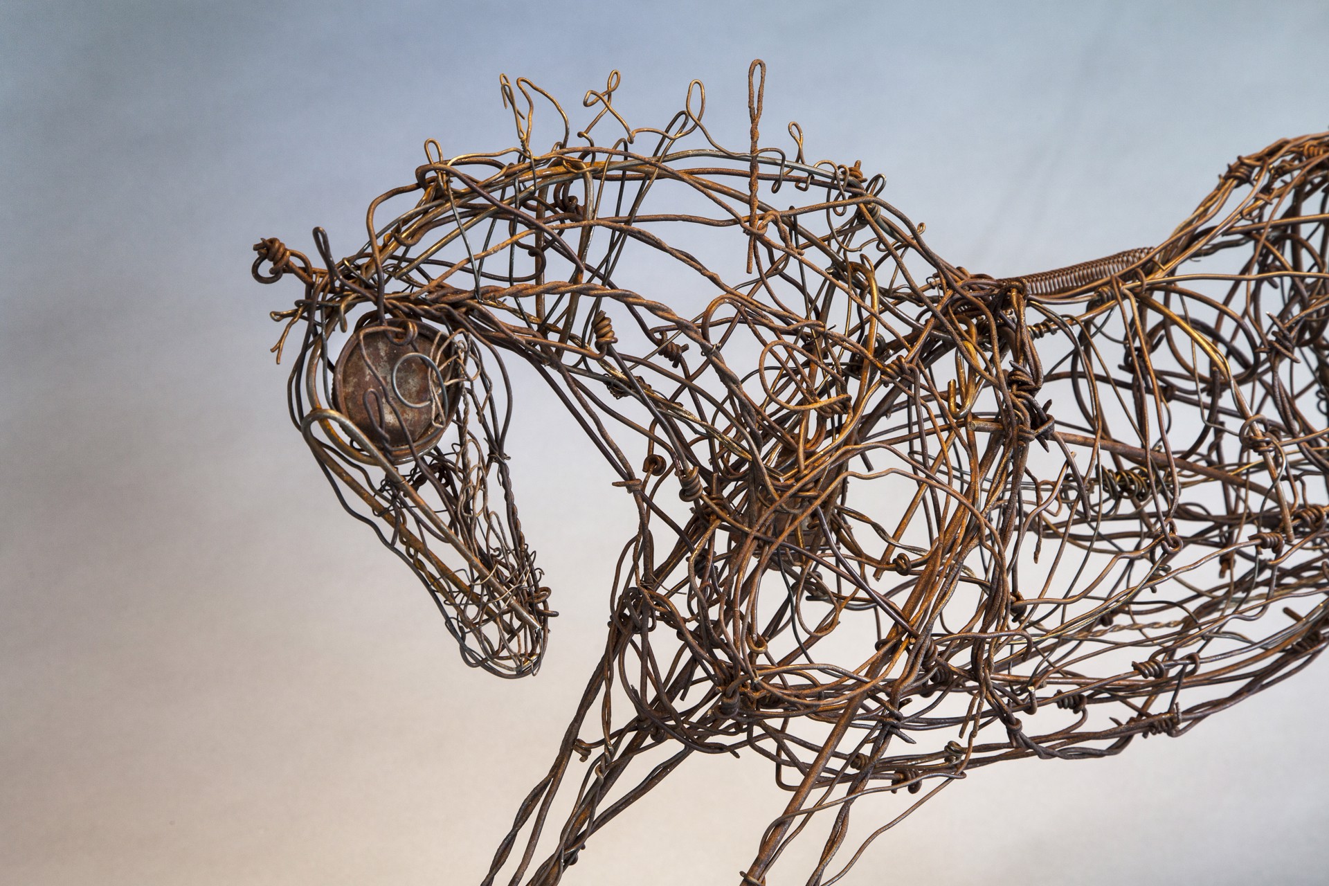 A wire sculpture of a horse on a metal stand.