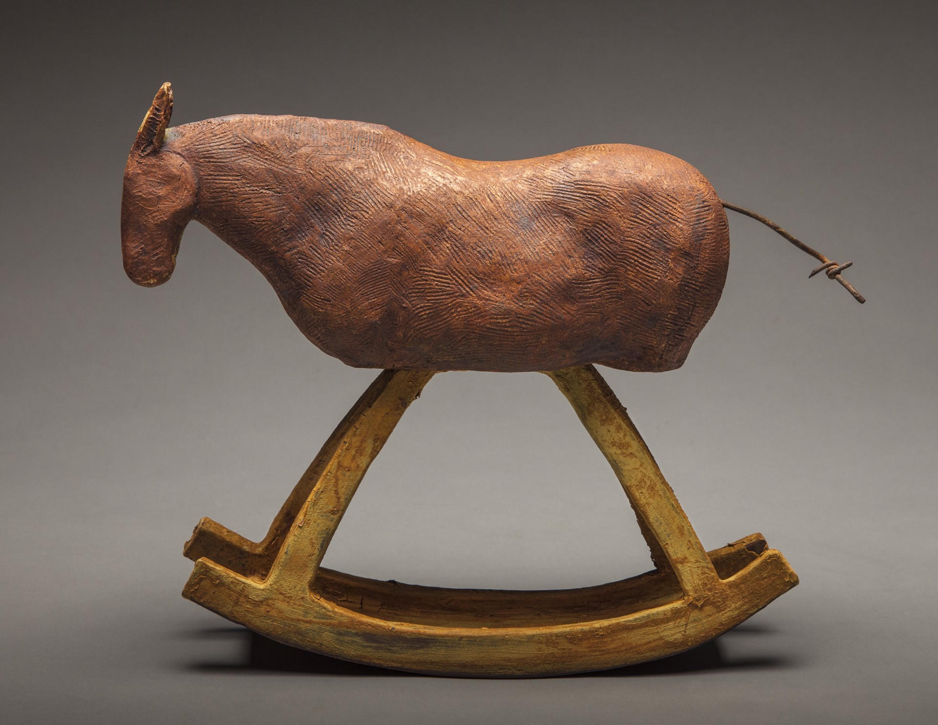 A rustic wooden rocking horse with a carved body and simple legs.