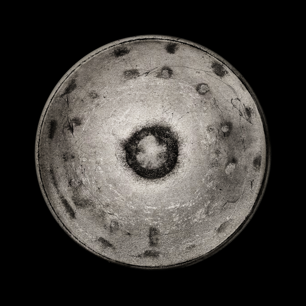 A black and white photo of a gong on a black background.