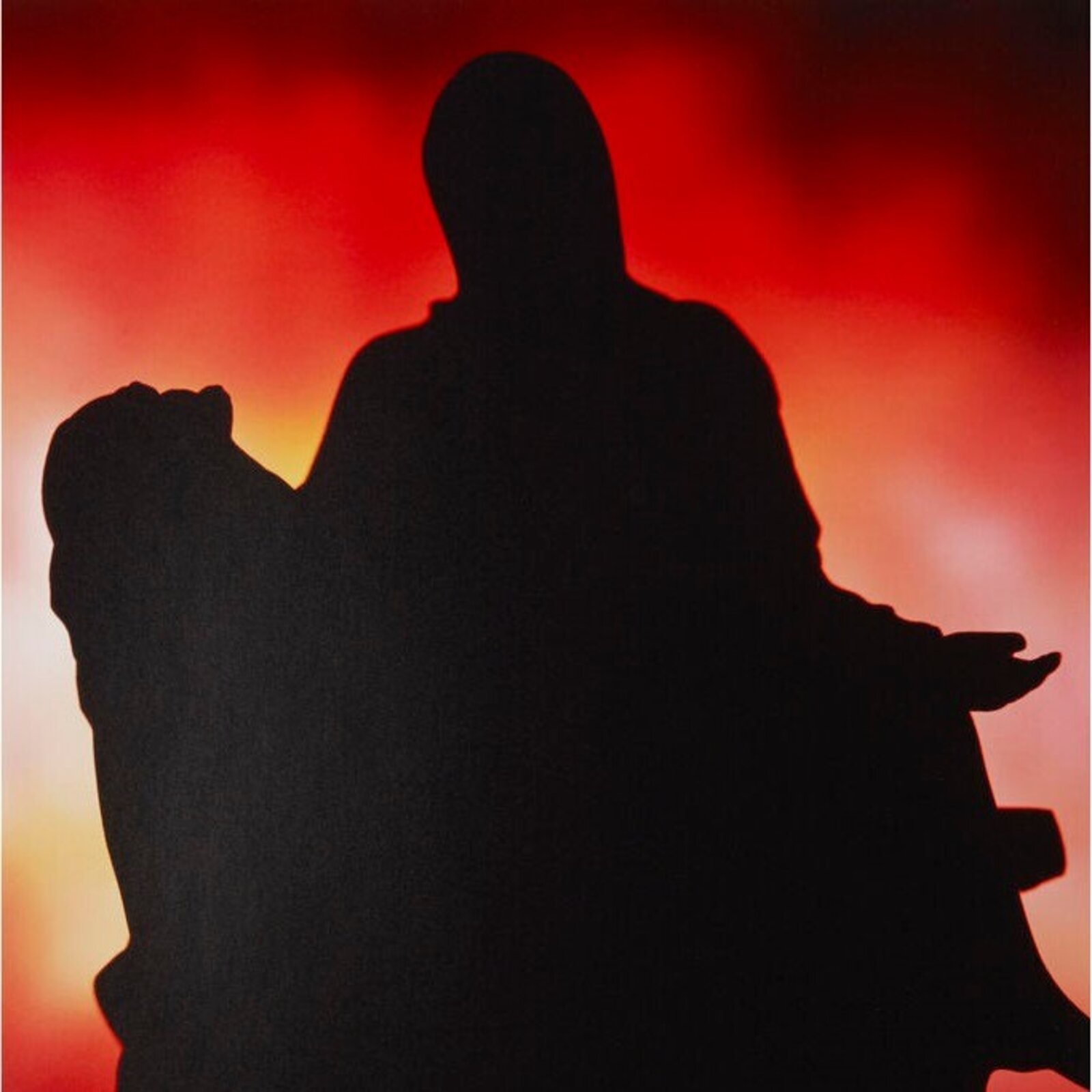 A framed print featuring a black silhouette of a figure against a fiery red and orange background.