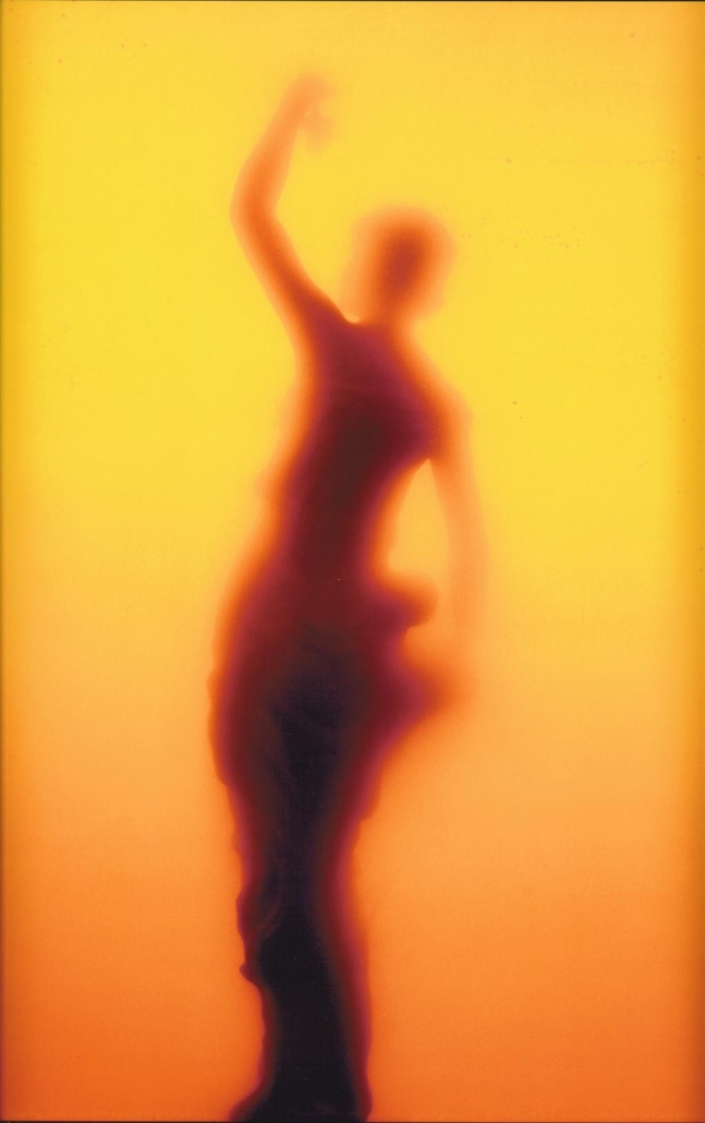 A silhouette of a woman dancing in front of a yellow background.