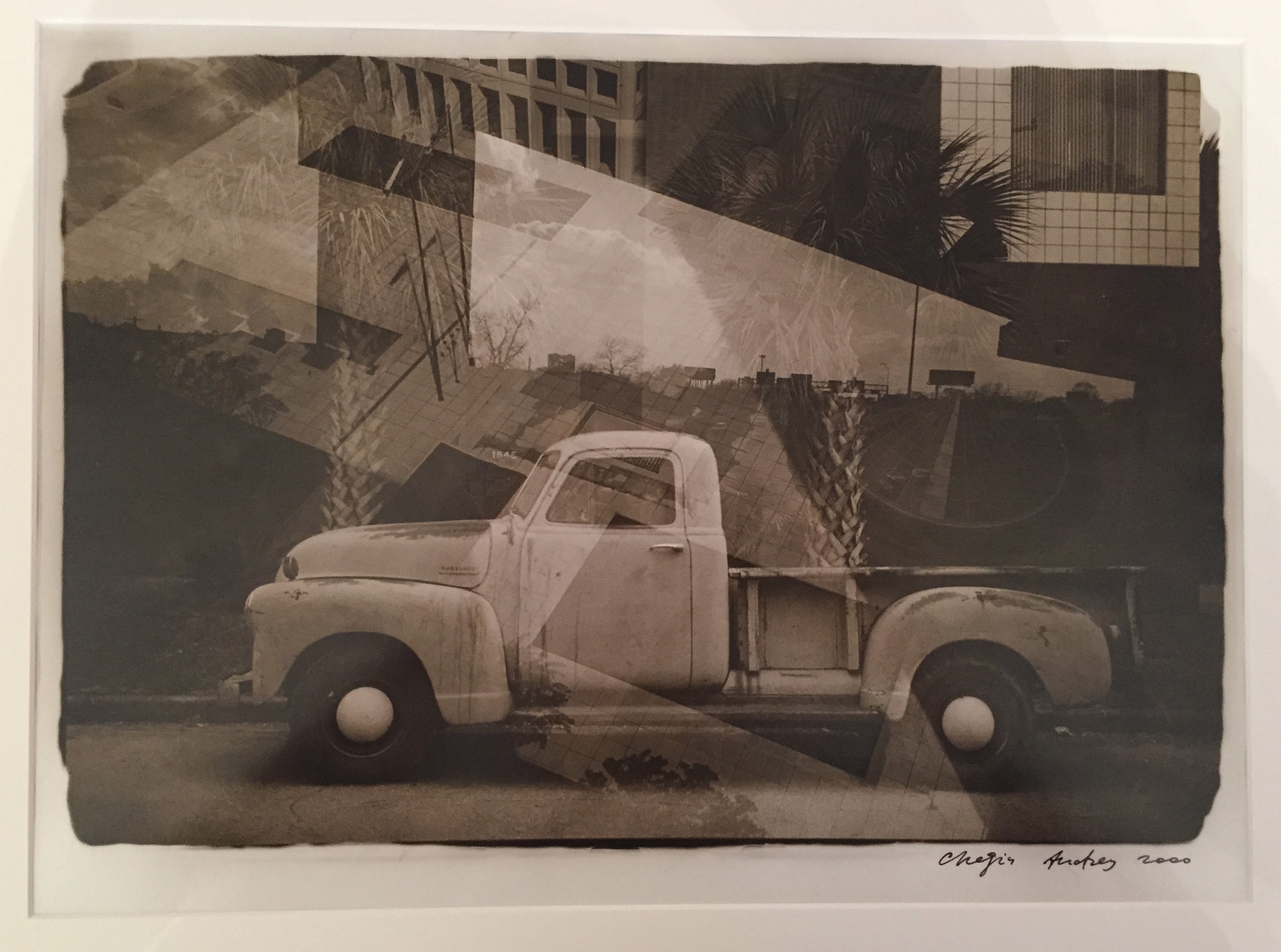 A black and white photo of an old truck parked in front of a building.