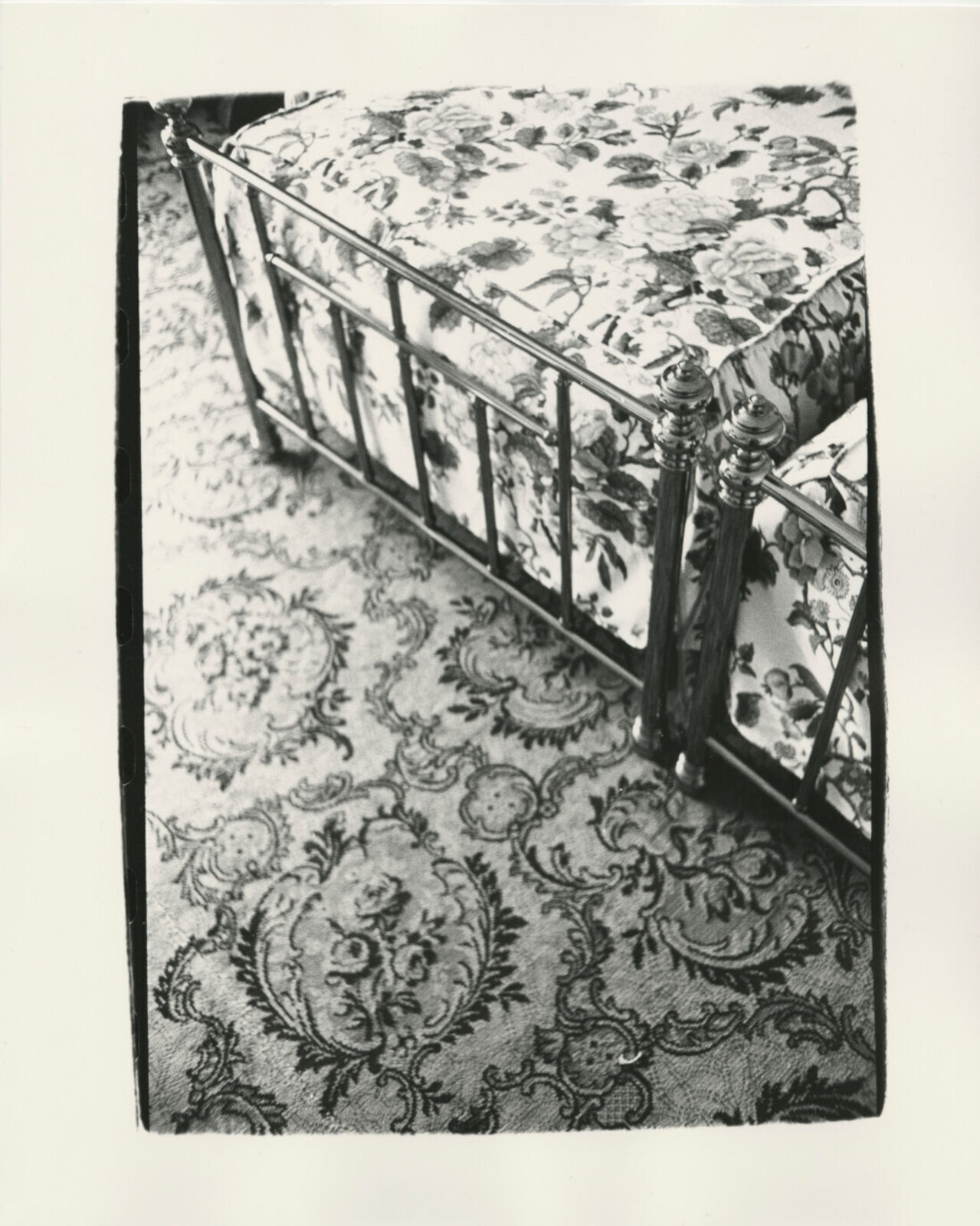A black and white photo of a bed in a room.