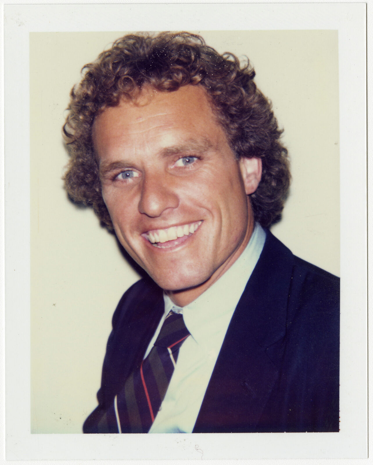 A man in a suit and tie smiles at the camera.