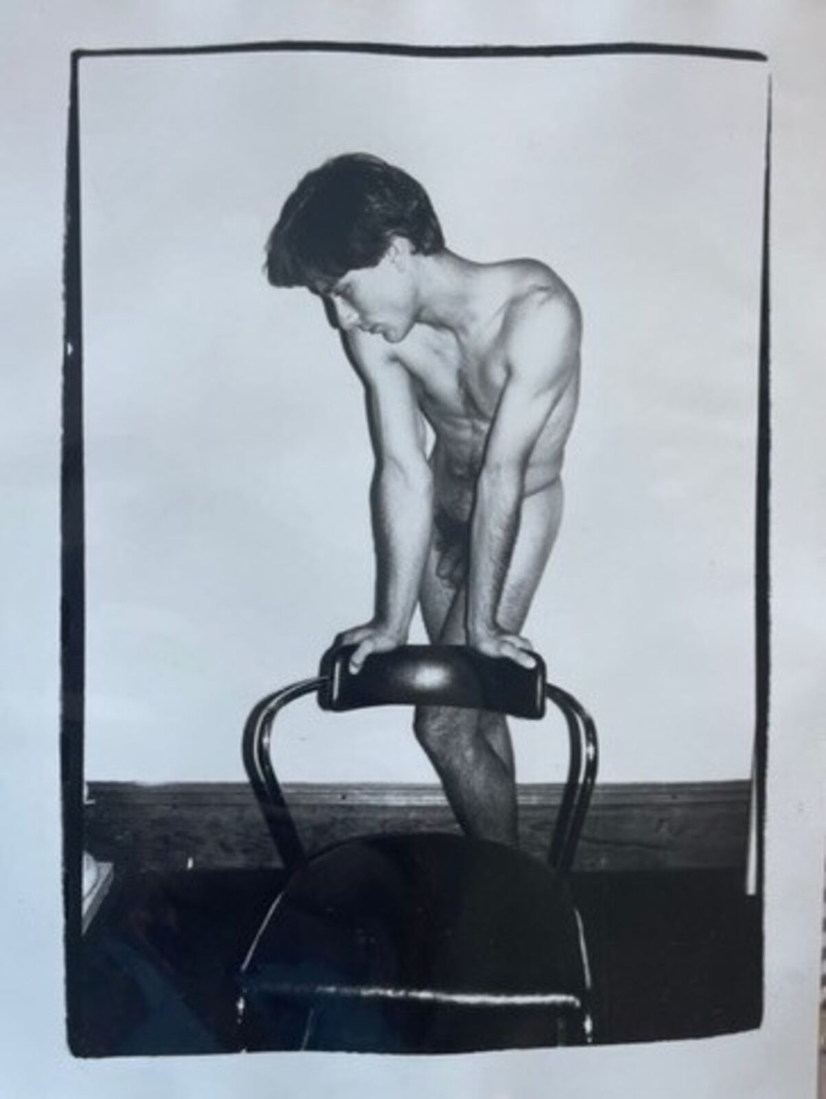 A black and white photo of a naked man on a stationary bike.