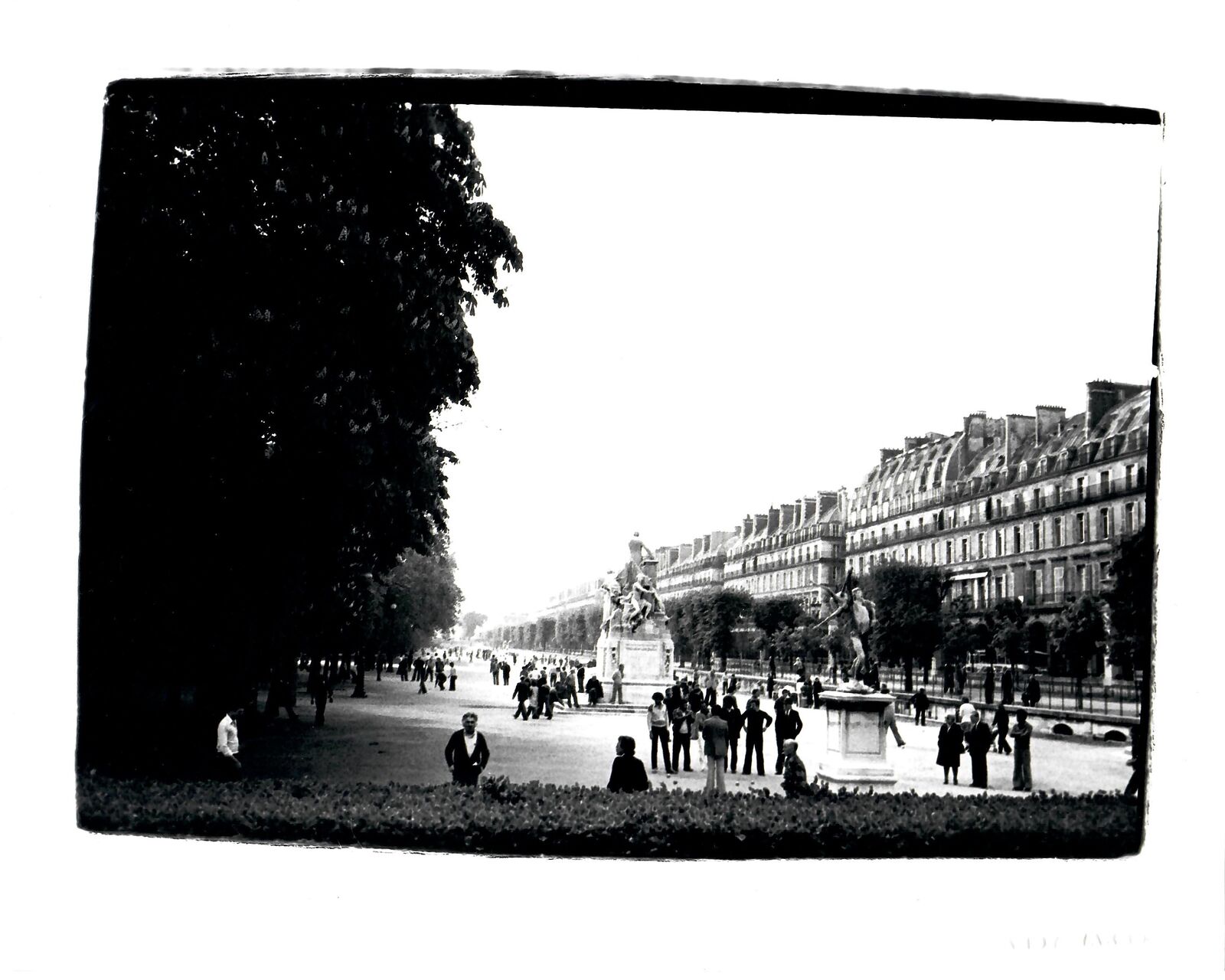 A black and white photo of people walking around a park.