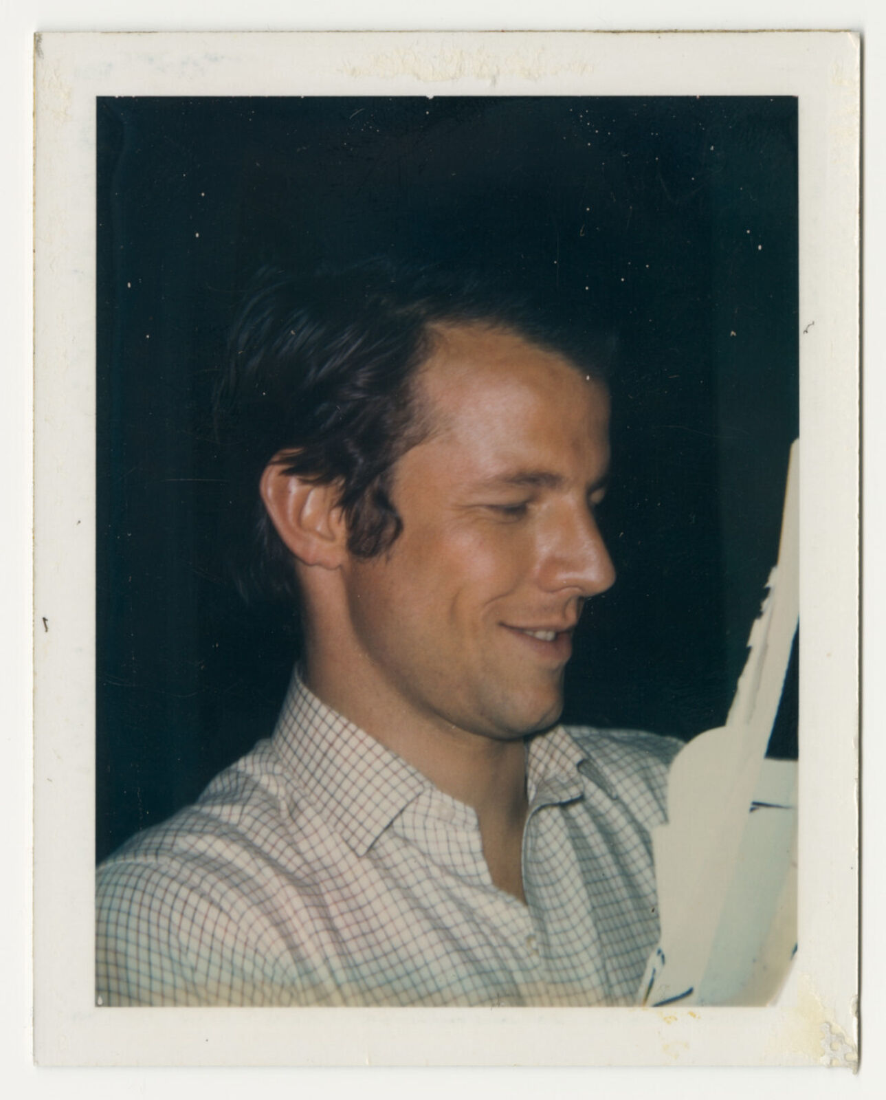 A man in a plaid shirt smiles at the camera. 