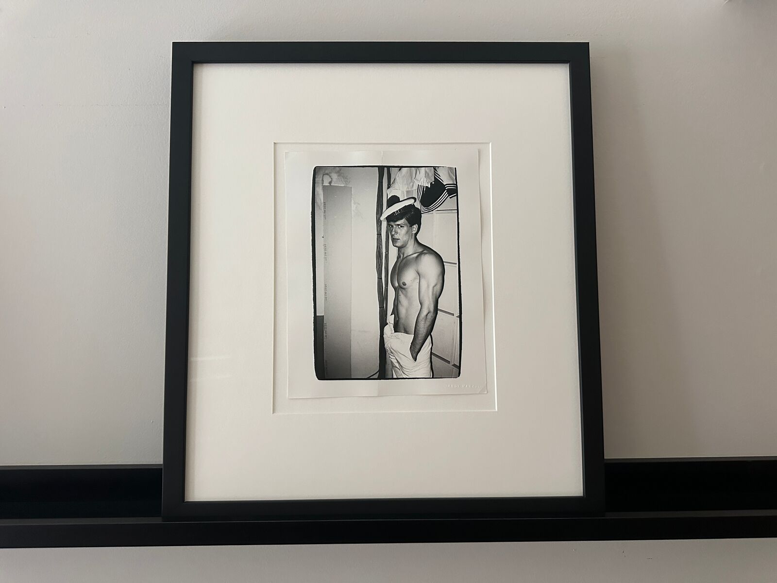 A shirtless man in a sailor's hat standing in front of a door.