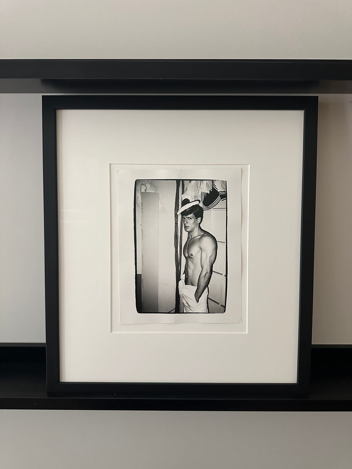A shirtless man in a sailor's hat standing in front of a door.
