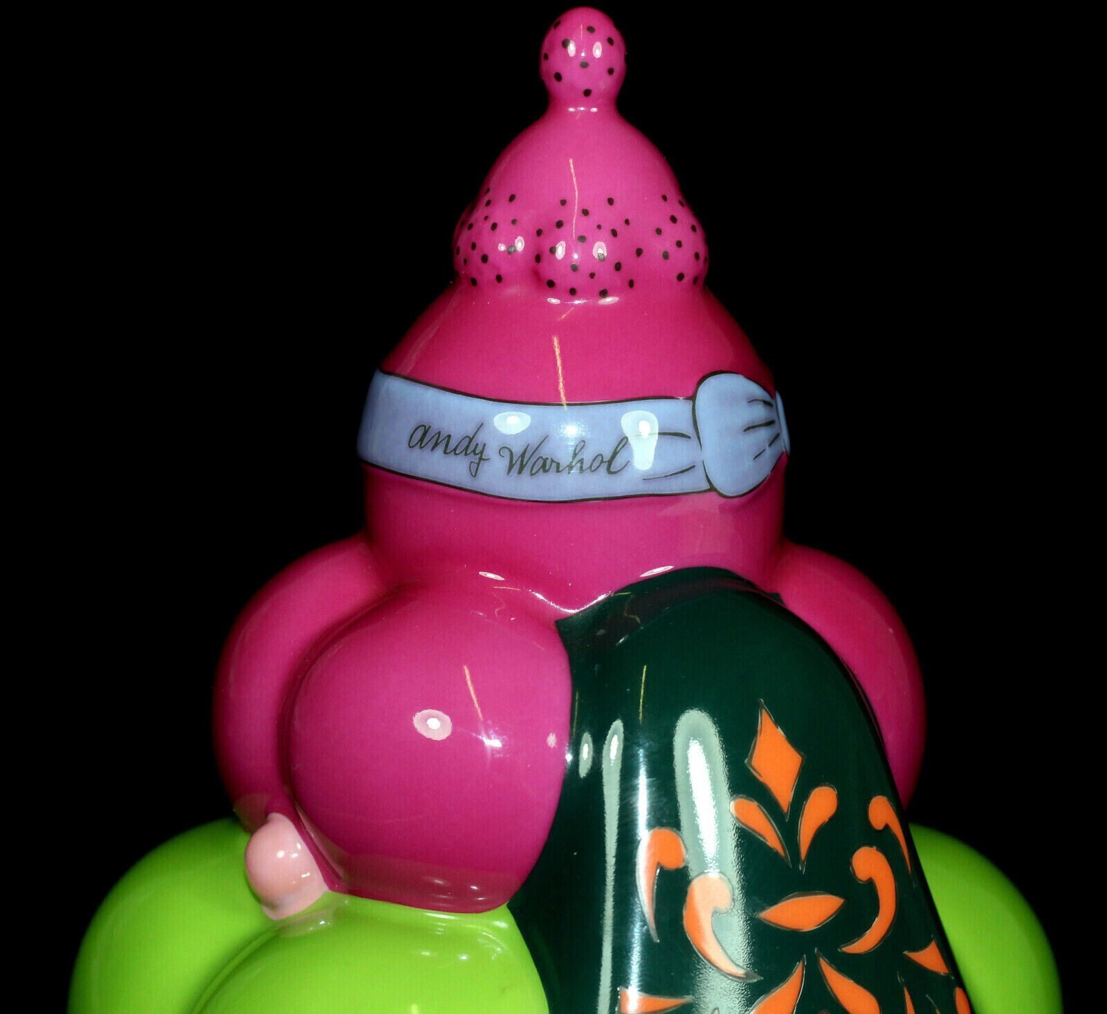 An orange vase with a pink hat on top of it.