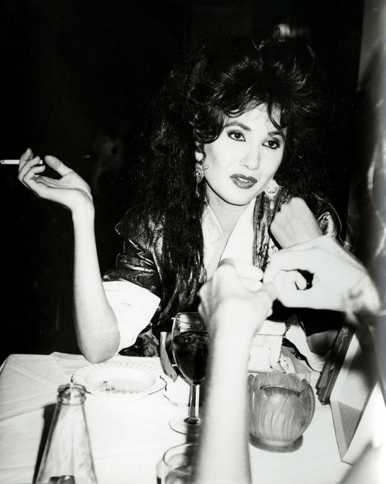 A woman sitting at a table smoking a cigarette.