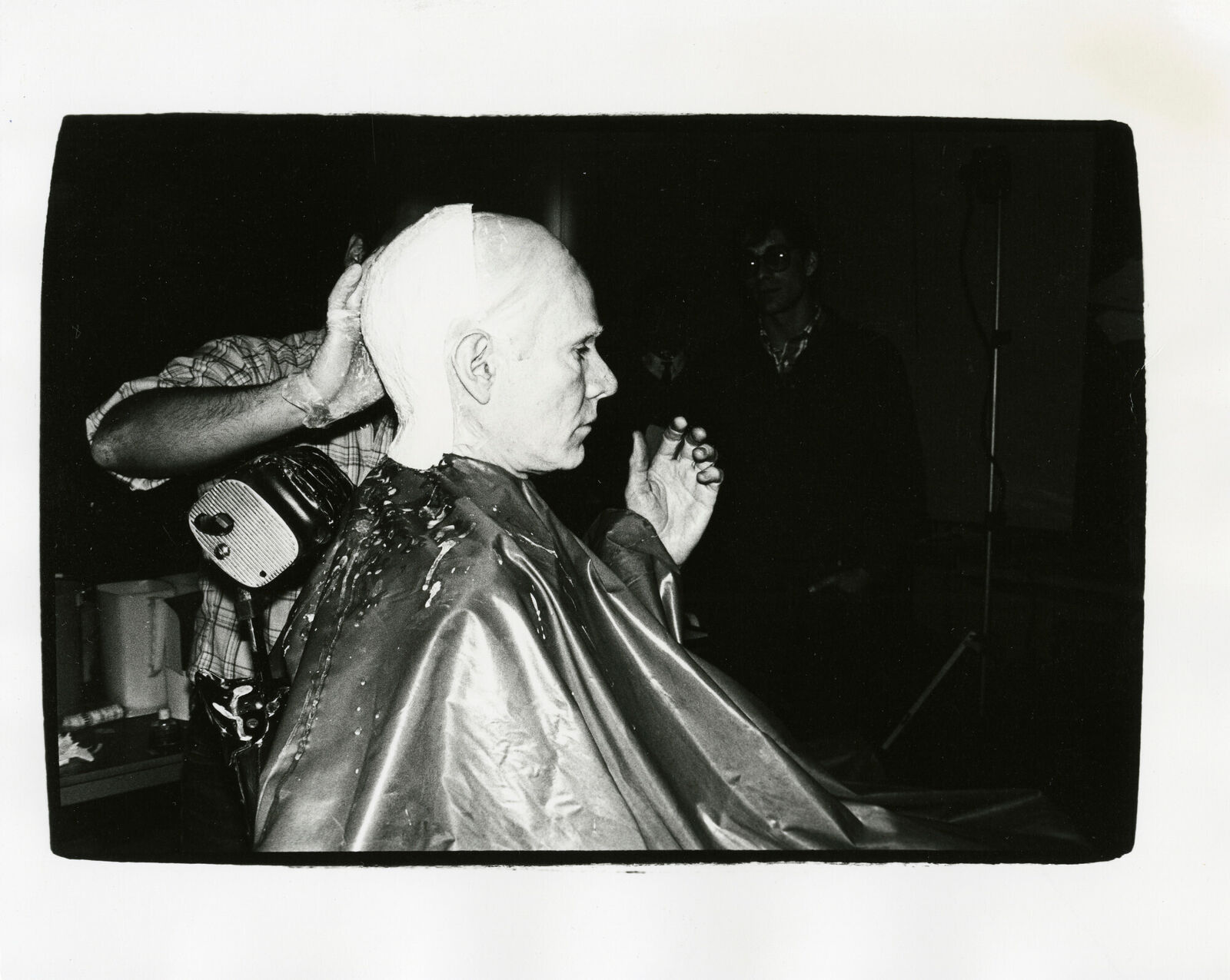 A black and white photo of a man getting his hair cut.