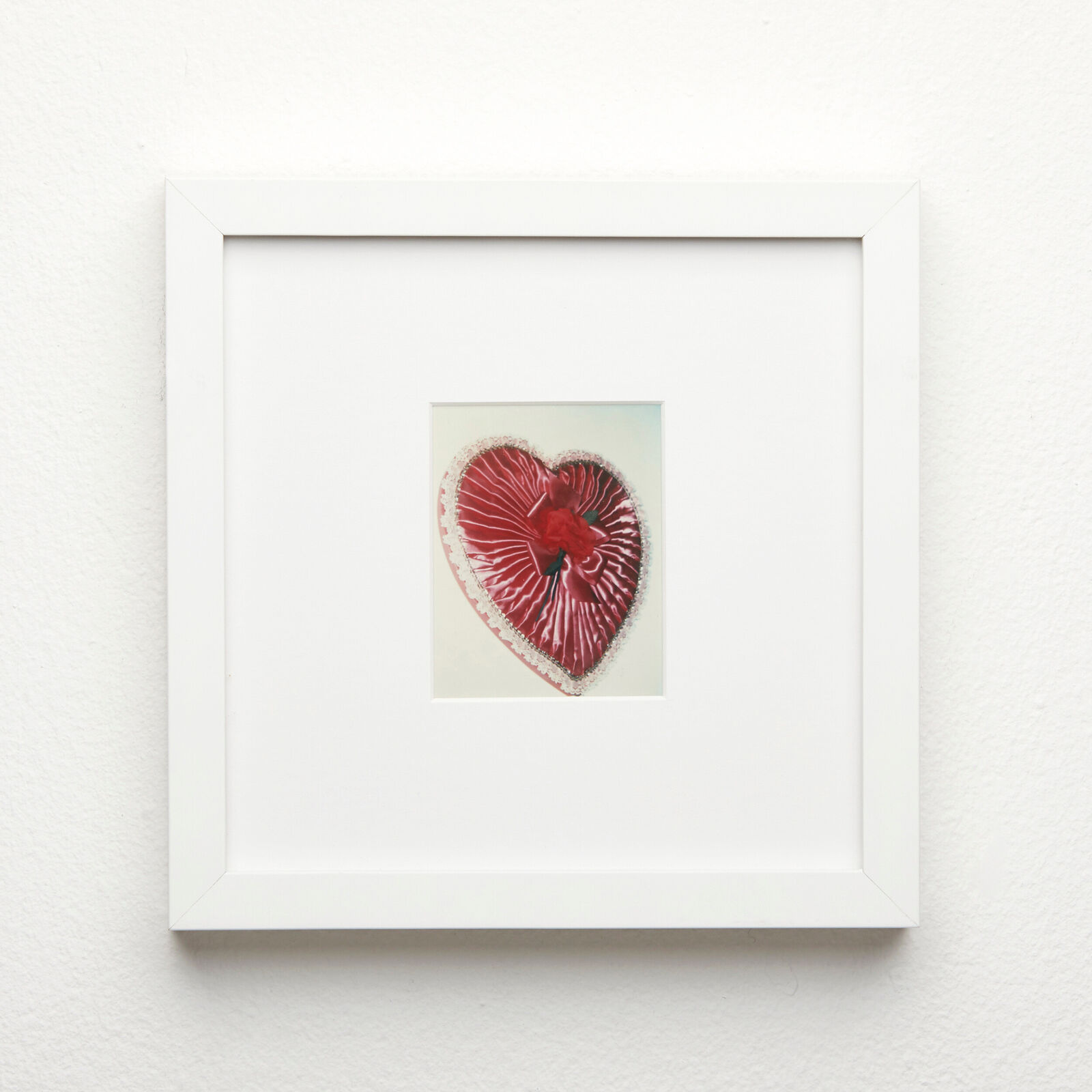A picture of a red heart in a white frame.