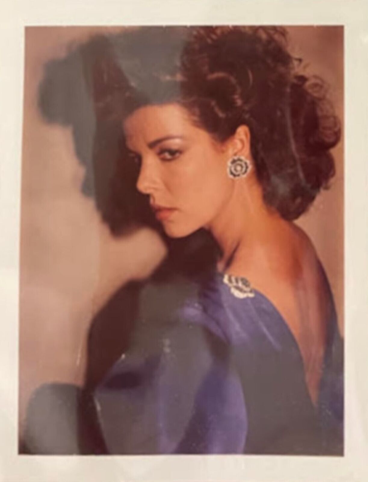 A polaroid photo of a woman in a blue dress.