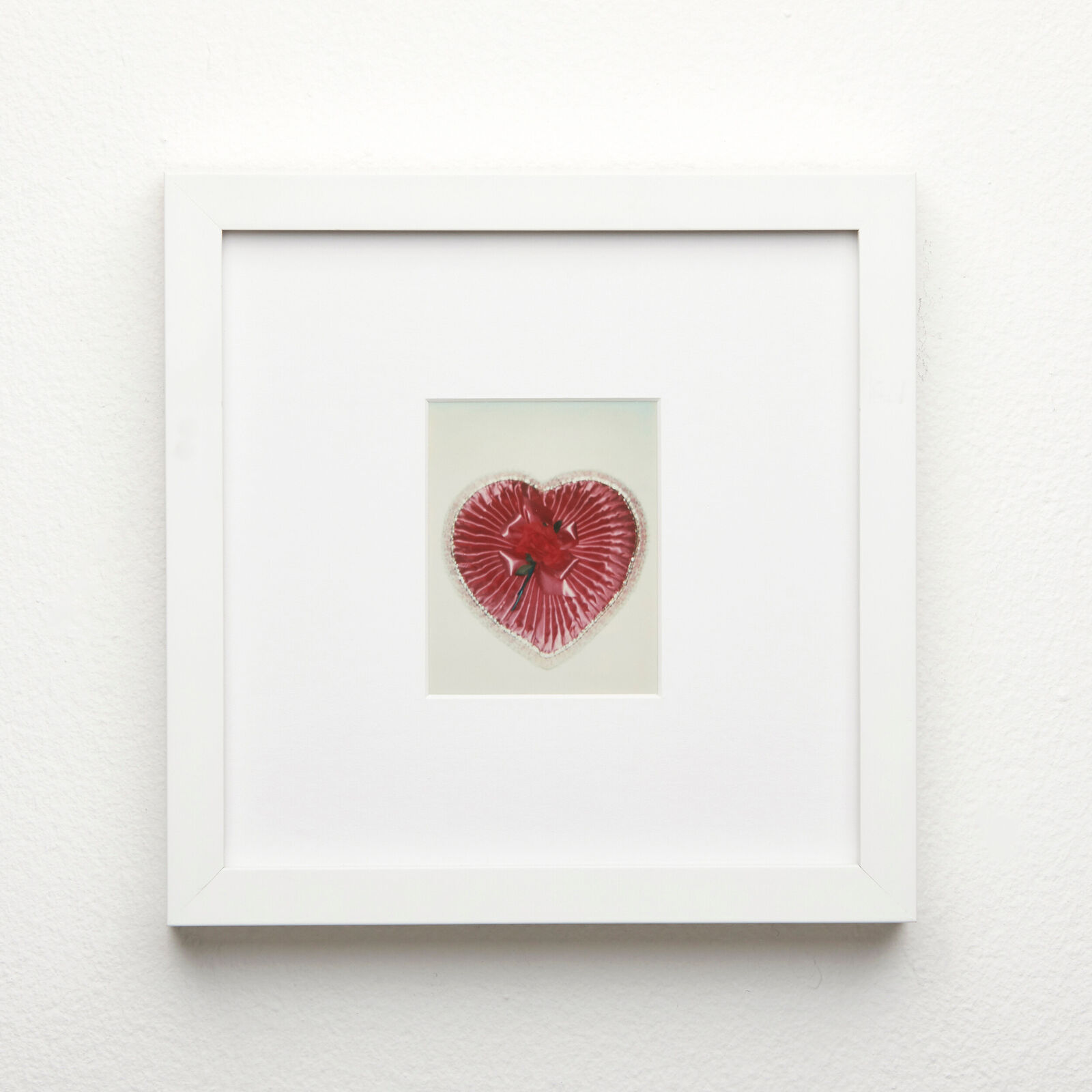 A picture of a red heart in a white frame.