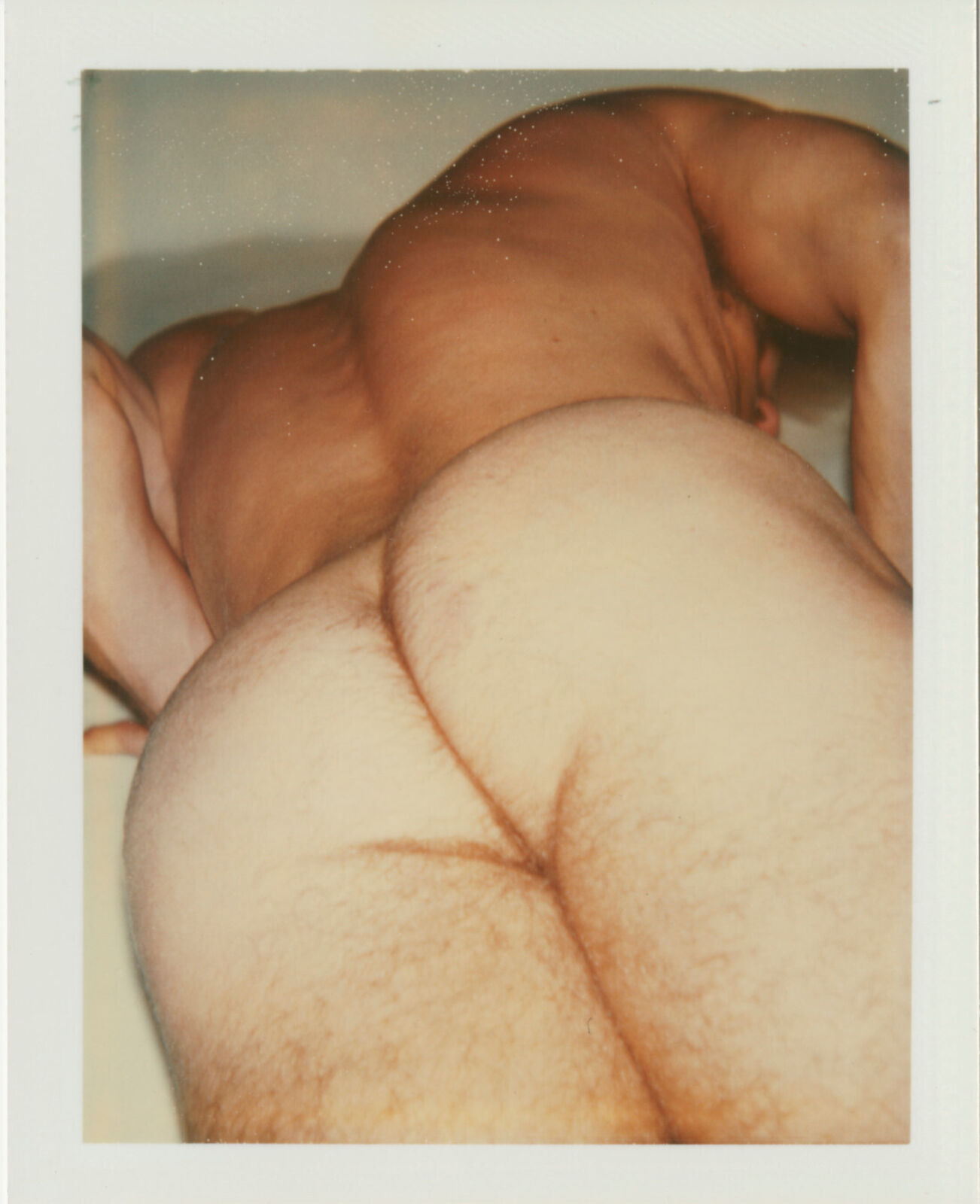 A picture of a naked man laying down on a bed.