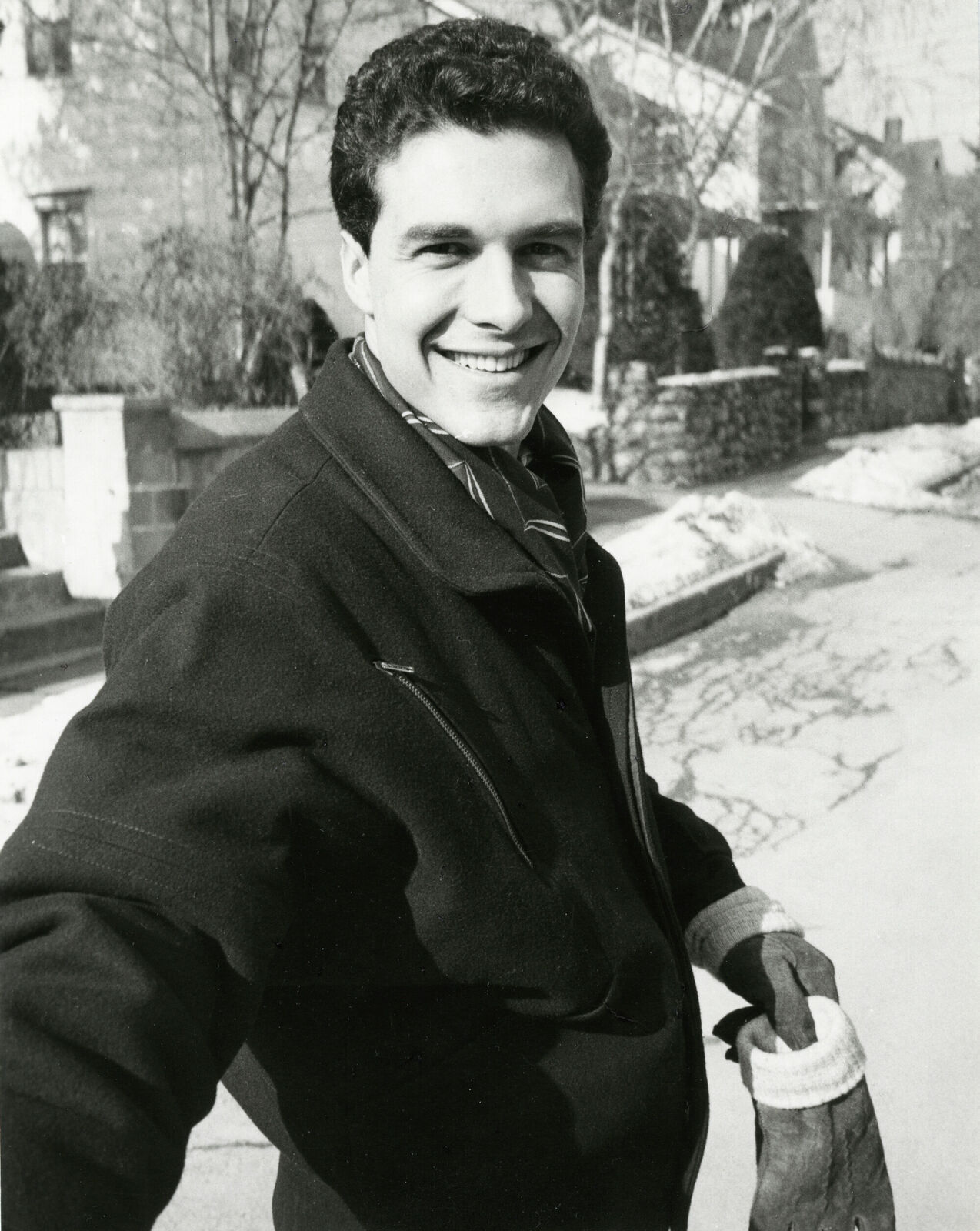 A black and white photo of a man in a coat and gloves.