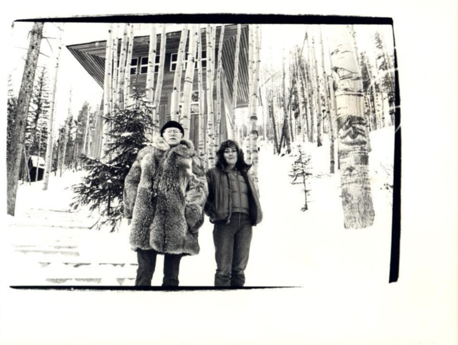 A black and white photo of two people standing in the snow.