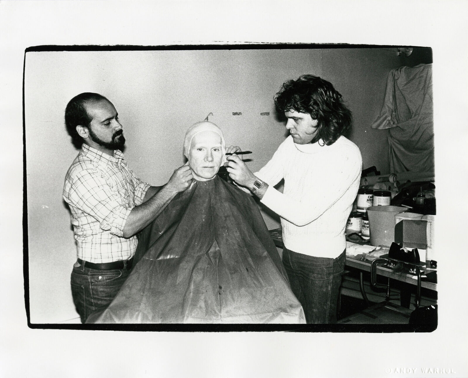 A black and white photo of a man getting his hair cut.