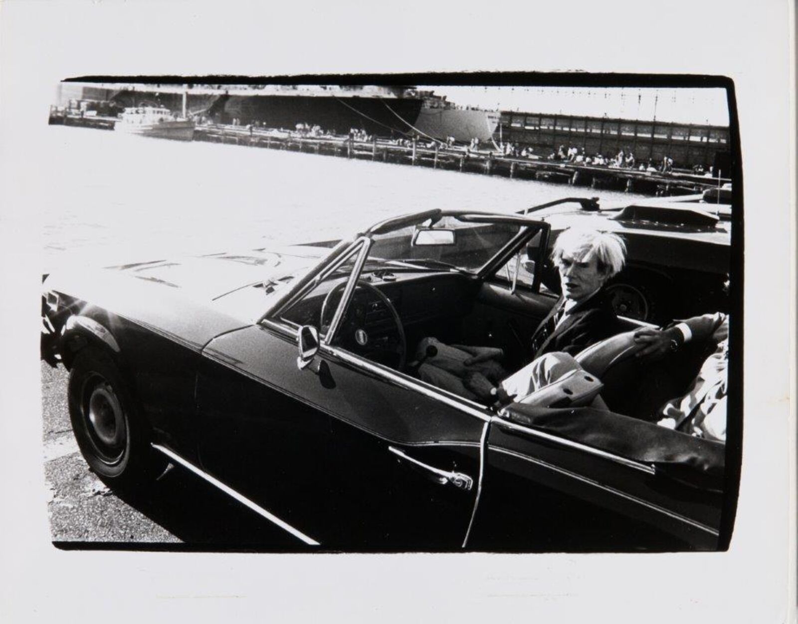 A black and white photo of a man sitting in a car.