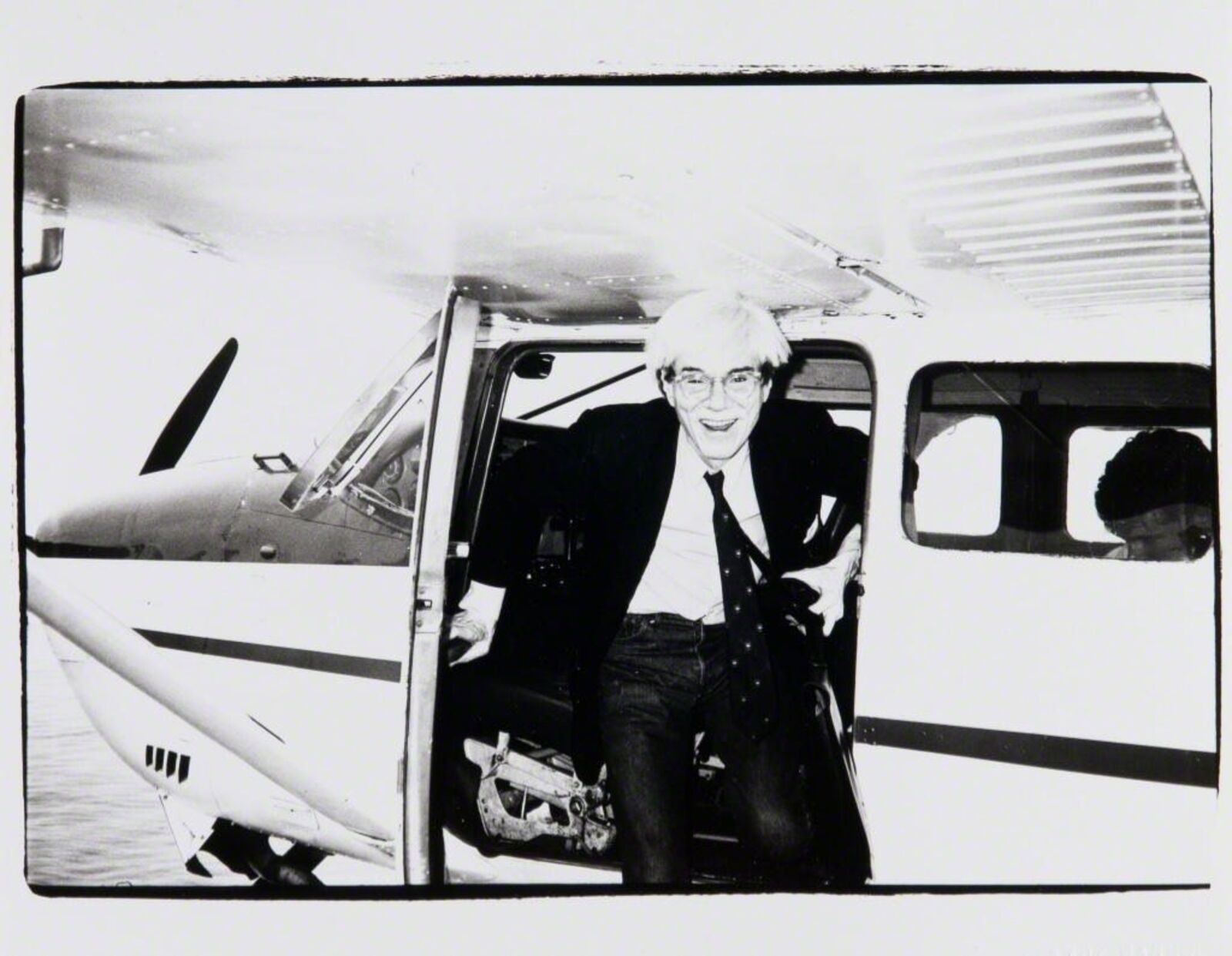 A black and white photo of a man sitting in the cockpit of a small plane.