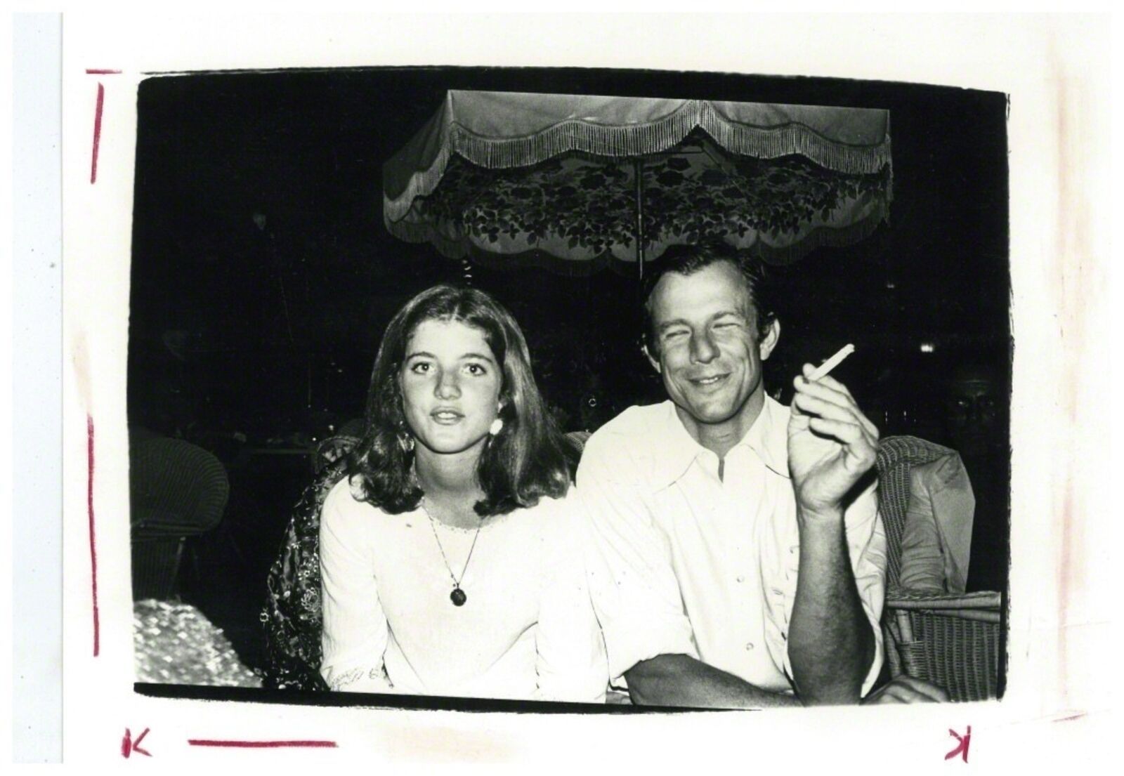 A man and a woman sitting next to each other smoking a cigarette.